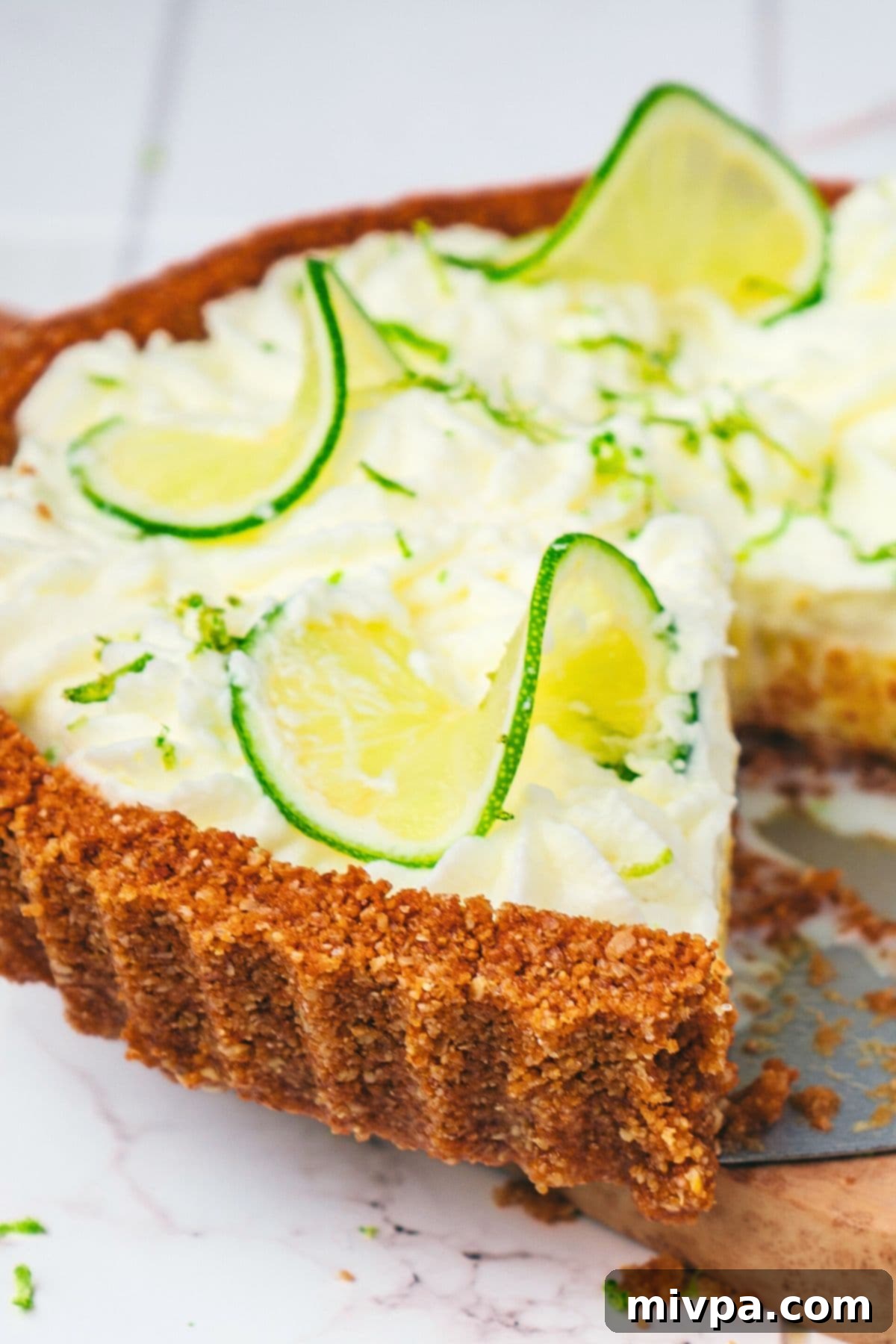 A half-eaten slice of gluten-free key lime pie, showcasing its thick, golden graham cracker crust and vibrant lime filling.