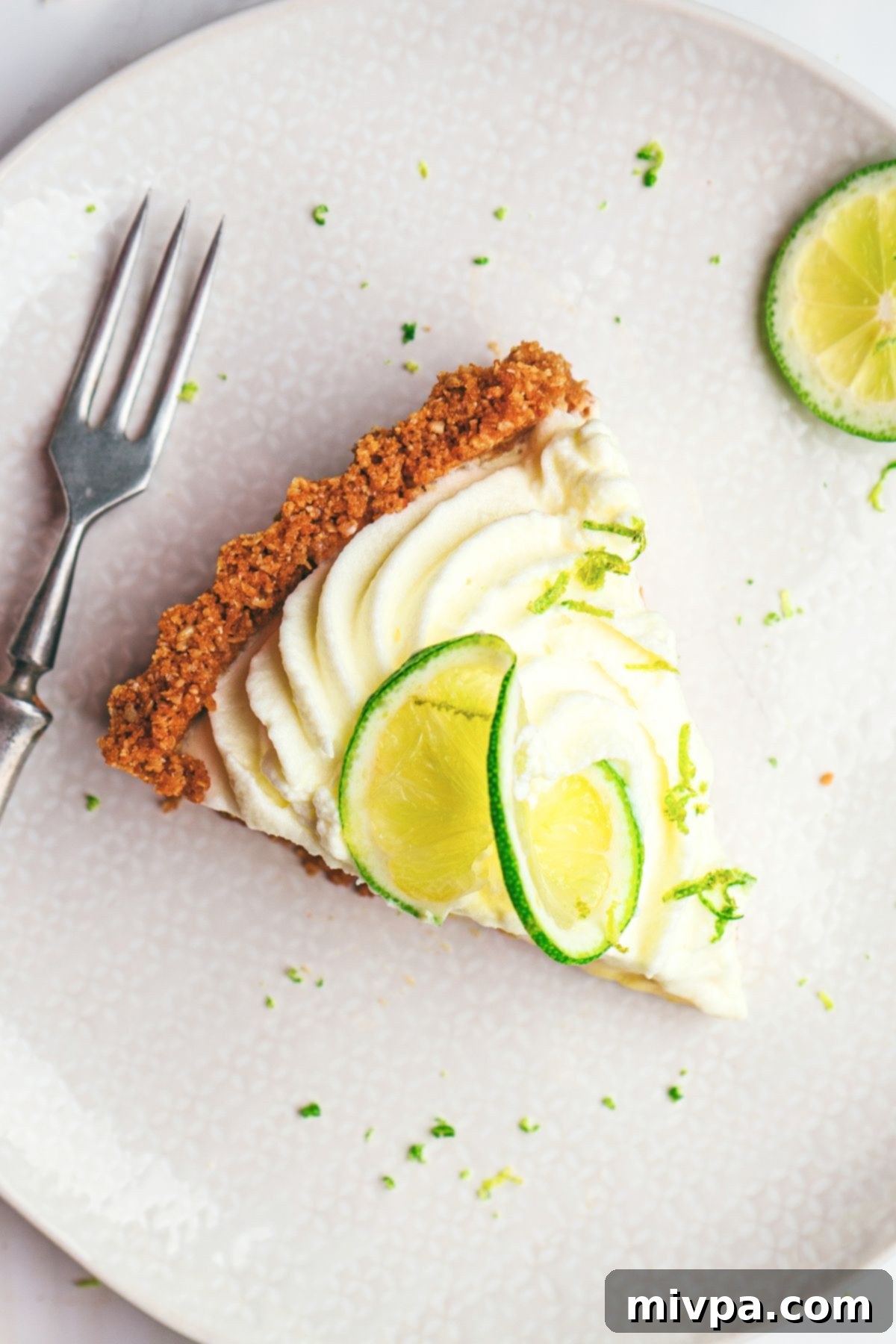 Top-down view of a beautifully presented slice of gluten-free key lime dessert with a dusting of lime zest on top of the whipped cream.