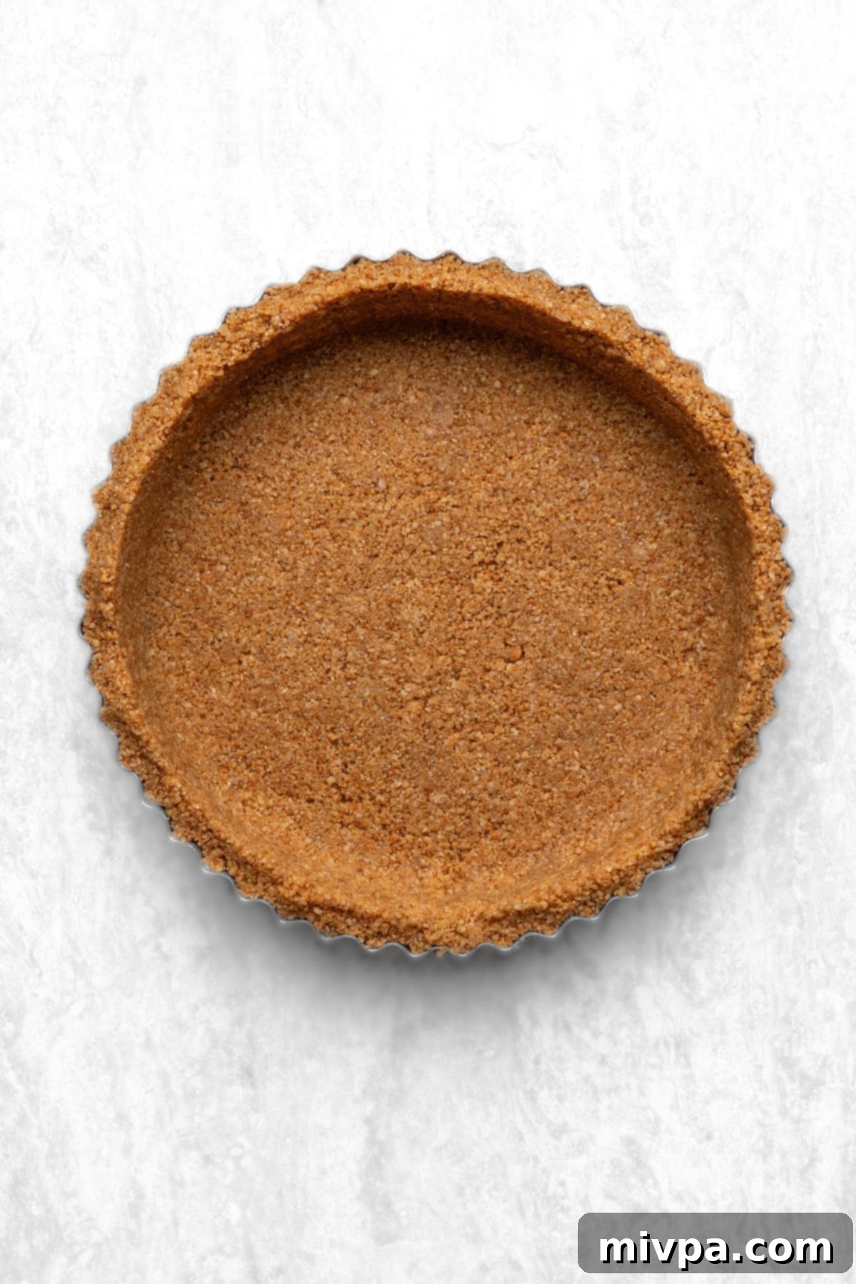 A perfectly baked gluten-free graham cracker crust cooling in a pie pan, ready for the filling.