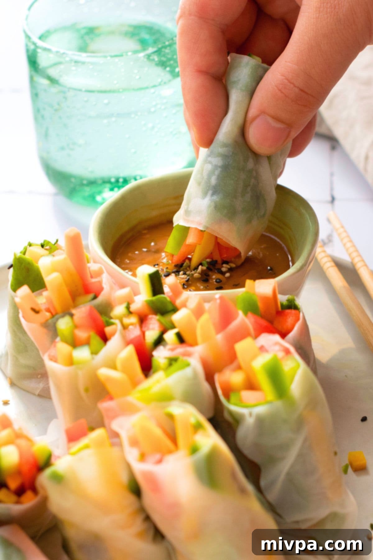 Dipping a vegetarian summer roll into a bowl of peanut sauce.