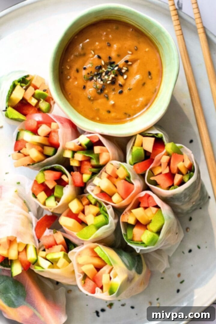 Top down view of fresh summer rolls and peanut sauce on a plate.