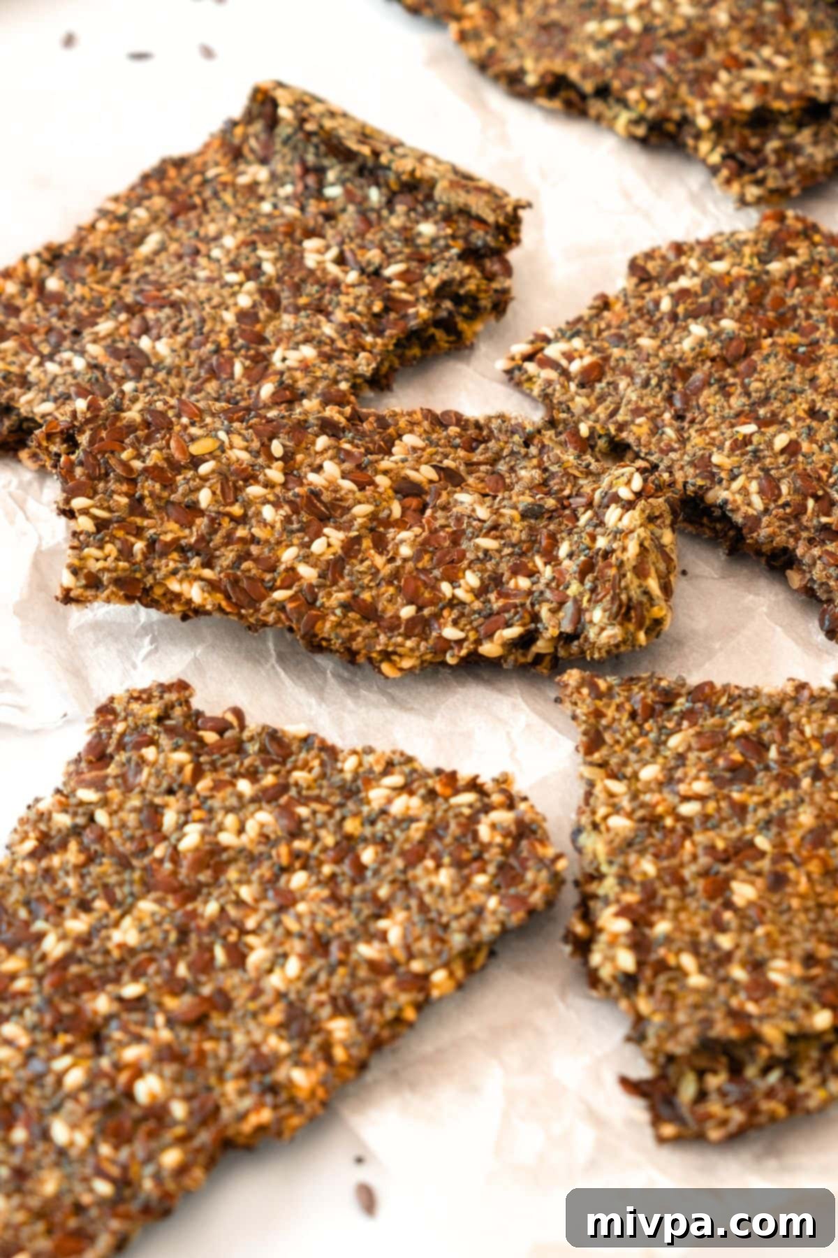 Homemade Flaxseed Meal Crackers A batch of freshly baked homemade flaxseed meal crackers cooling on parchment paper, ready to be broken into pieces.