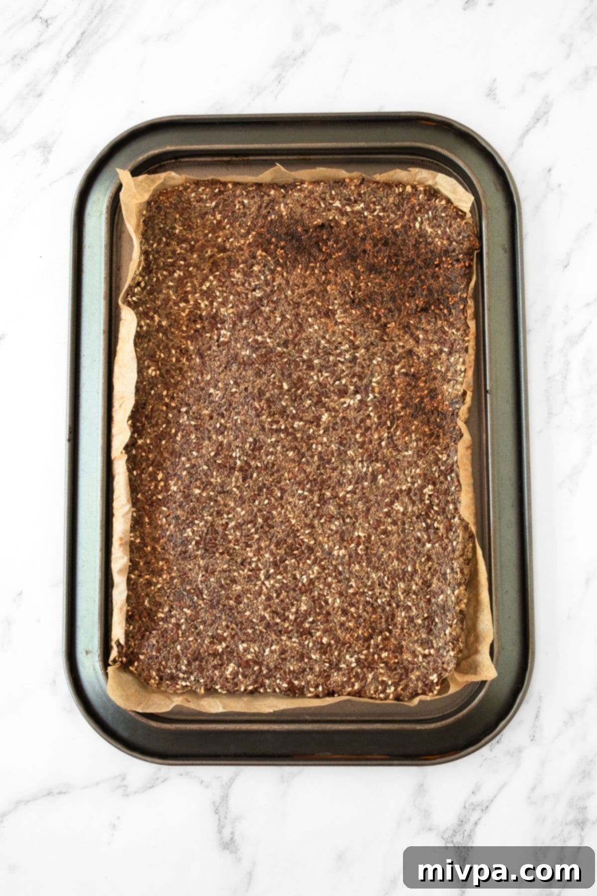 Homemade Flaxseed Crackers (Gluten-Free) Baked The golden-brown, baked flaxseed mixture still in the baking sheet, indicating its readiness and crispy texture.