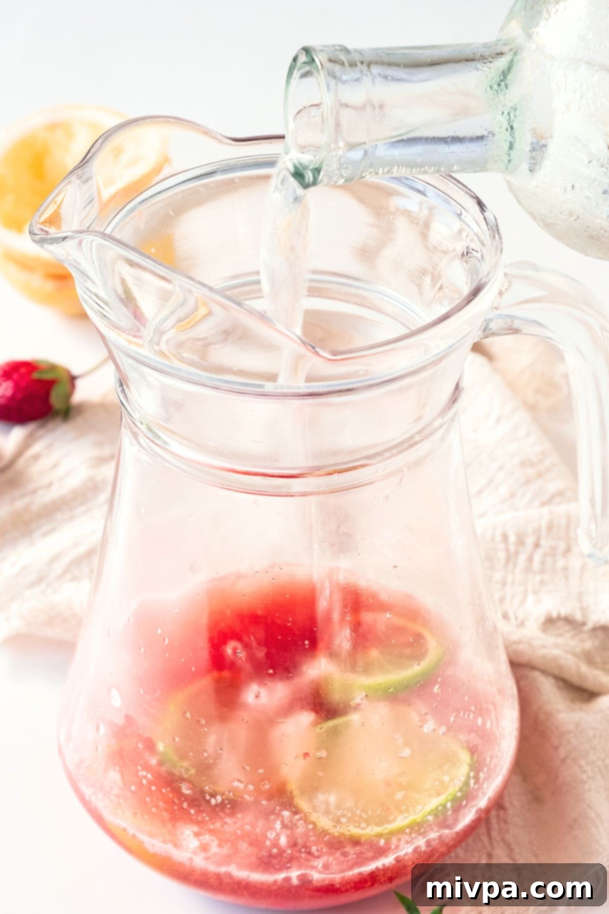 Strawberry Sparkling Lemonade Pouring sparkling water into a jug of strawberry syrup.