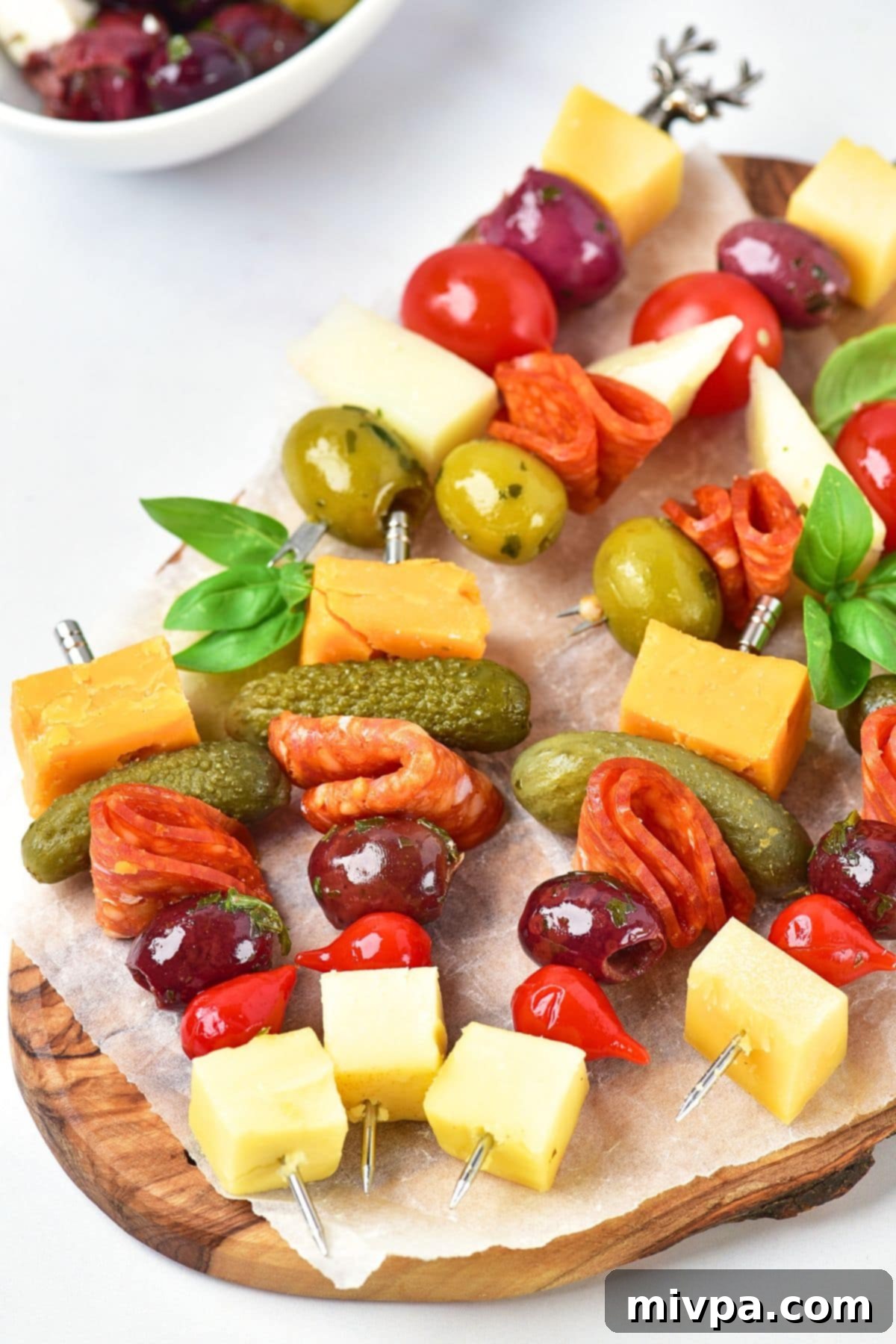 Charcuterie skewers on parchment-lined wooden board.