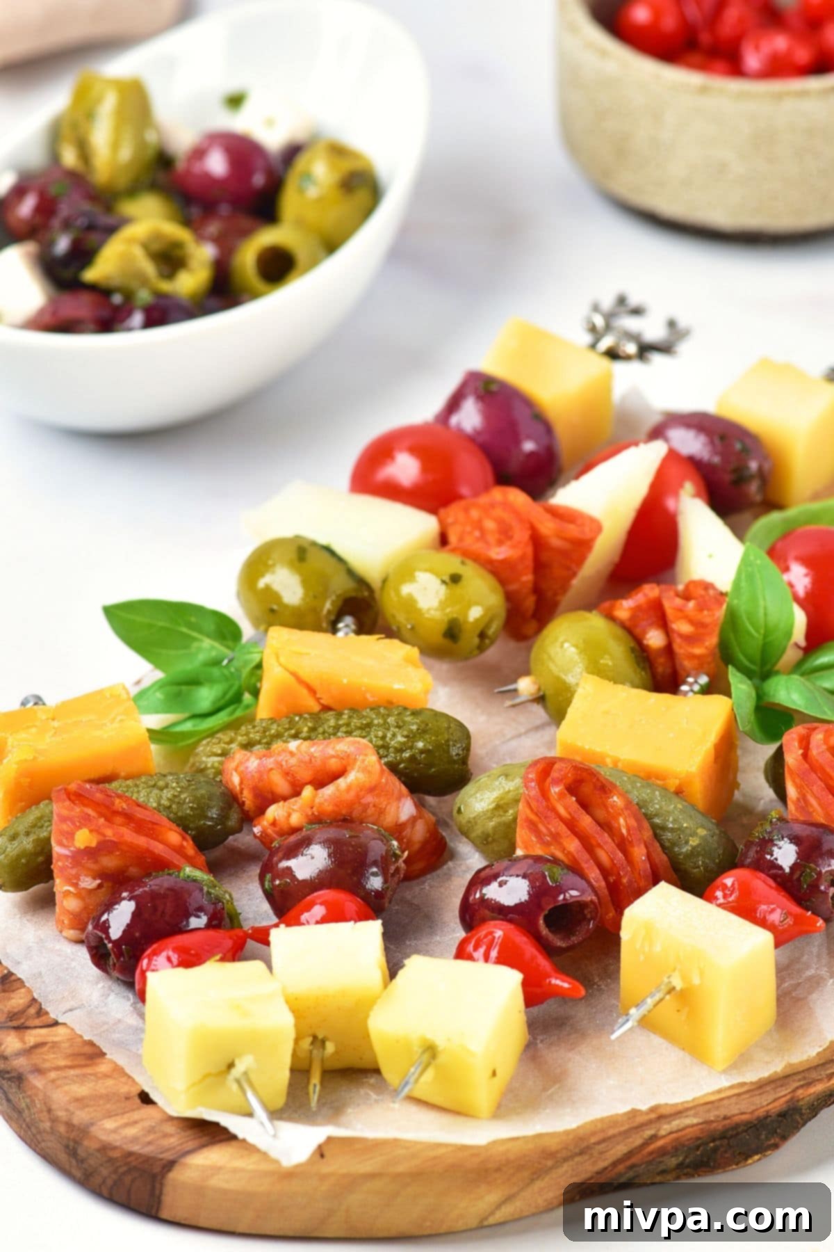 Antipasto skewers on parchment-lined wooden board.