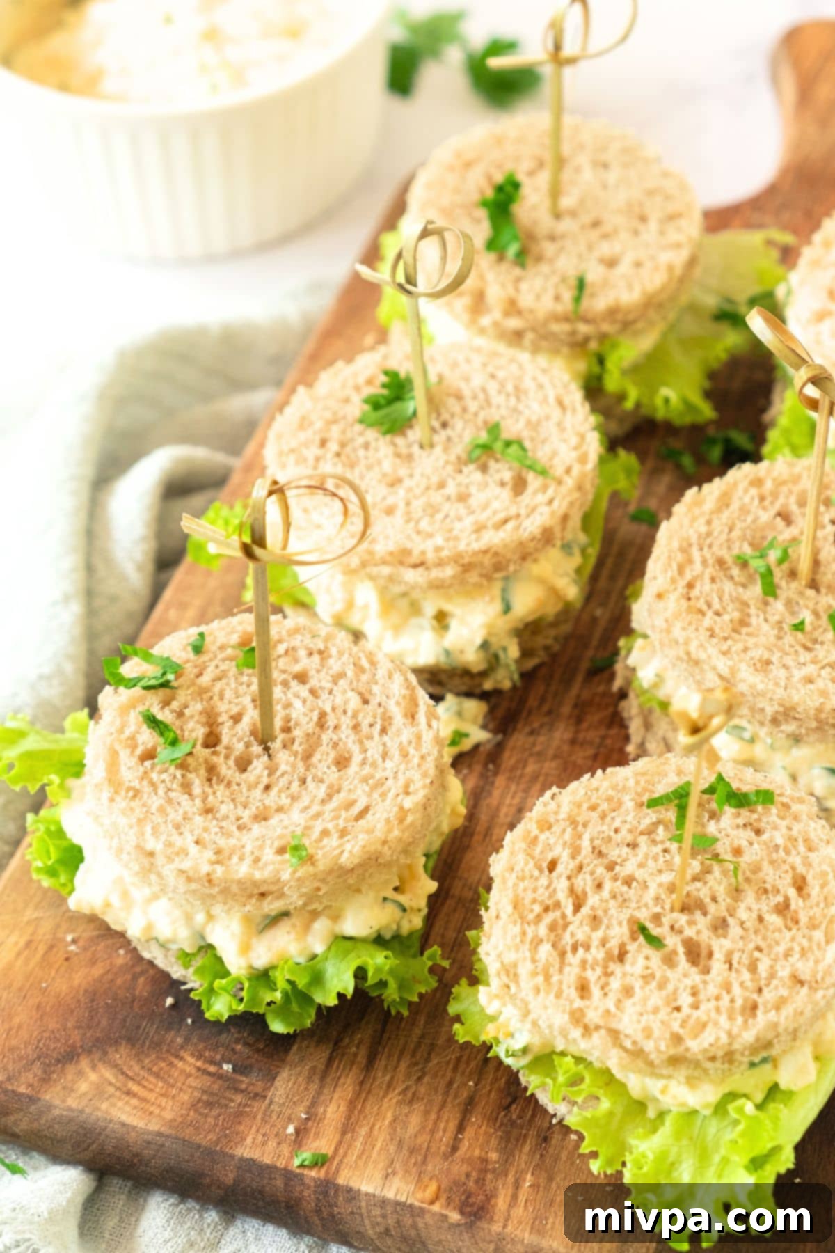 Egg salad sandwiches on wooden board.