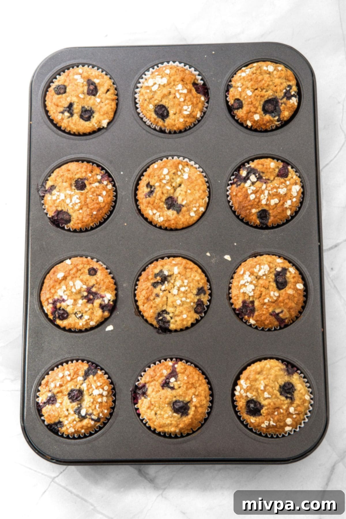 Freshly baked blueberry banana oat muffins, golden brown and perfectly risen from the oven.