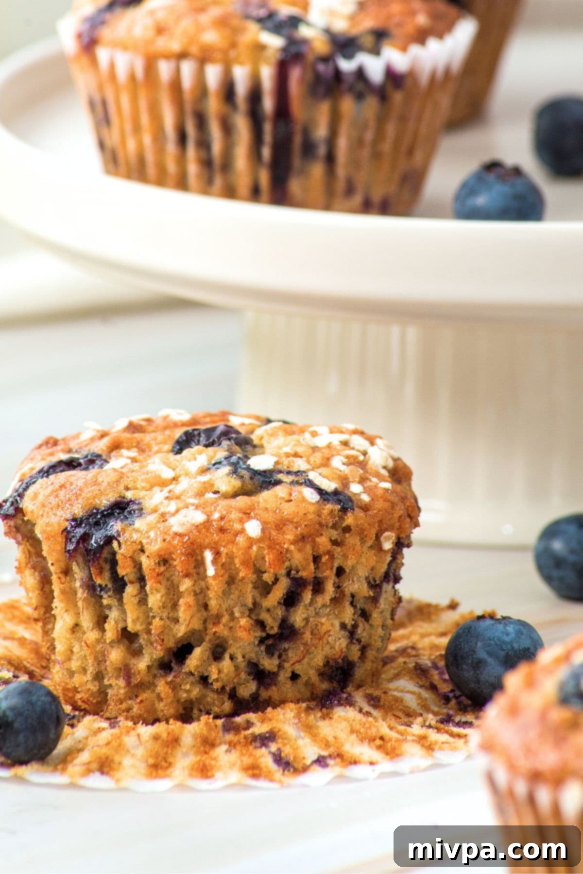 A single blueberry oat muffin resting in its liner on a cooling rack.