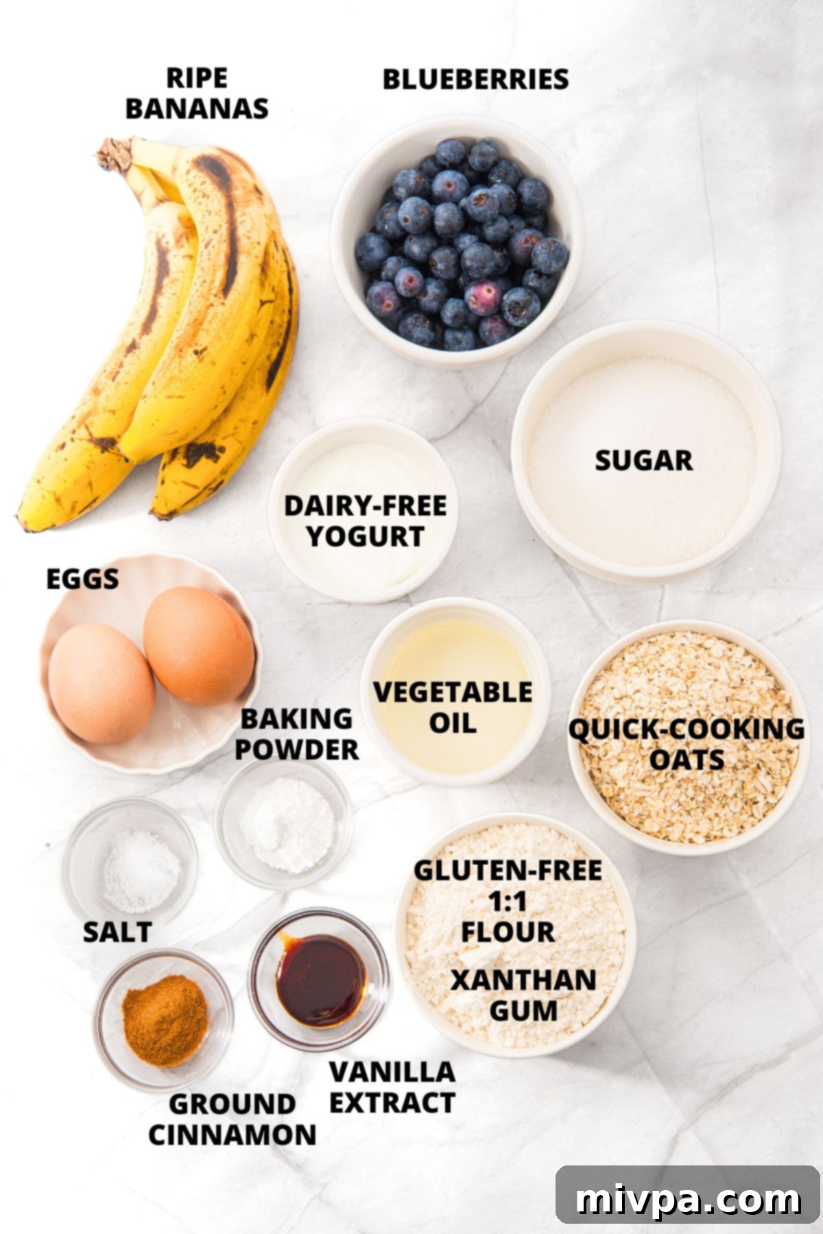 Ingredients for banana blueberry oatmeal muffins recipe laid out neatly on a white board.