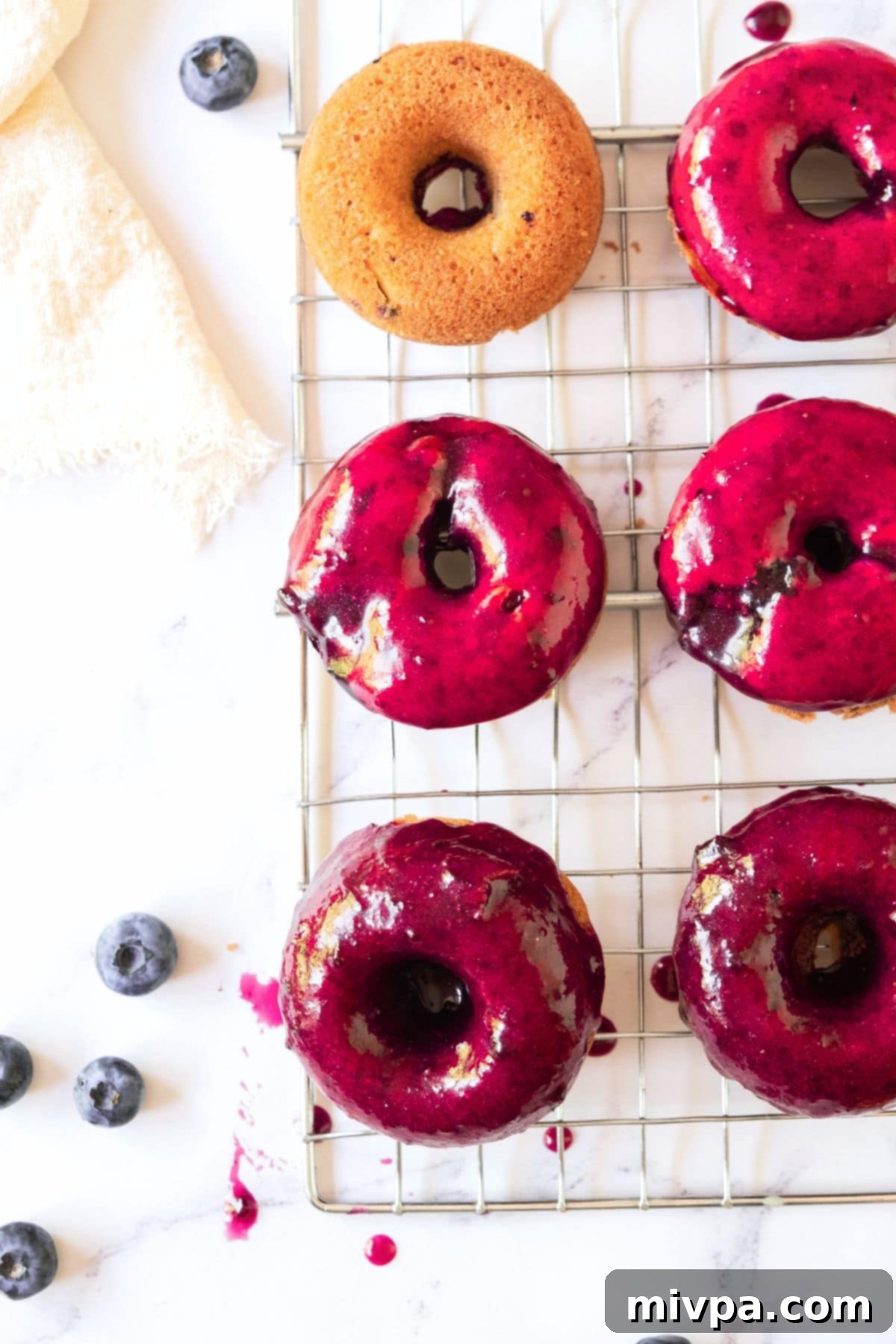 Blueberry Donut Glaze (Gluten-Free, Vegan) Two donuts richly coated in a beautiful blueberry donut glaze, ready to be enjoyed.