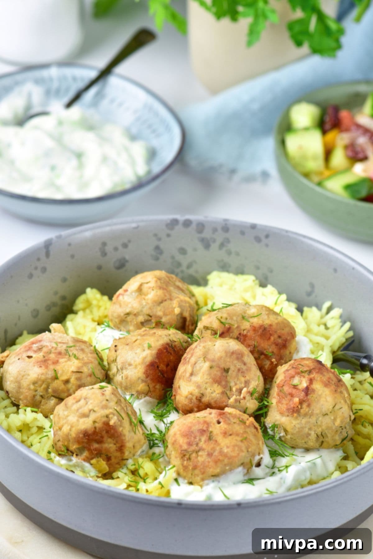 A close-up view of a bowl of turkey and feta meatballs served with golden yellow rice, ready to eat.
