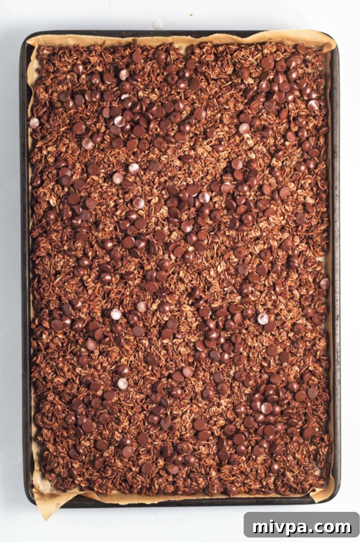 Easy Chocolate Granola Recipe (Gluten-Free, Vegan) Granola topped with chocolate chips in baking sheet