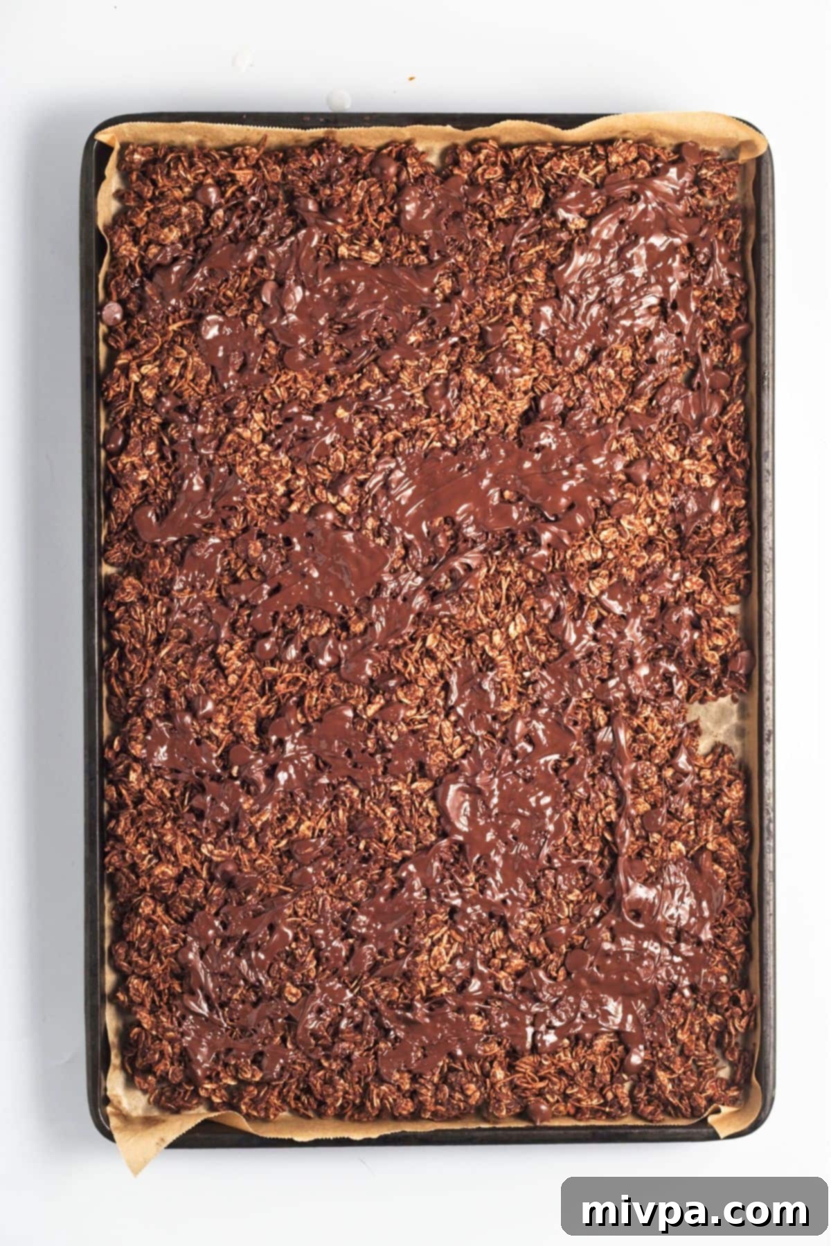 Decadent Gluten Free Vegan Chocolate Coconut Granola 2 Spreading melted chocolate over granola mixture.