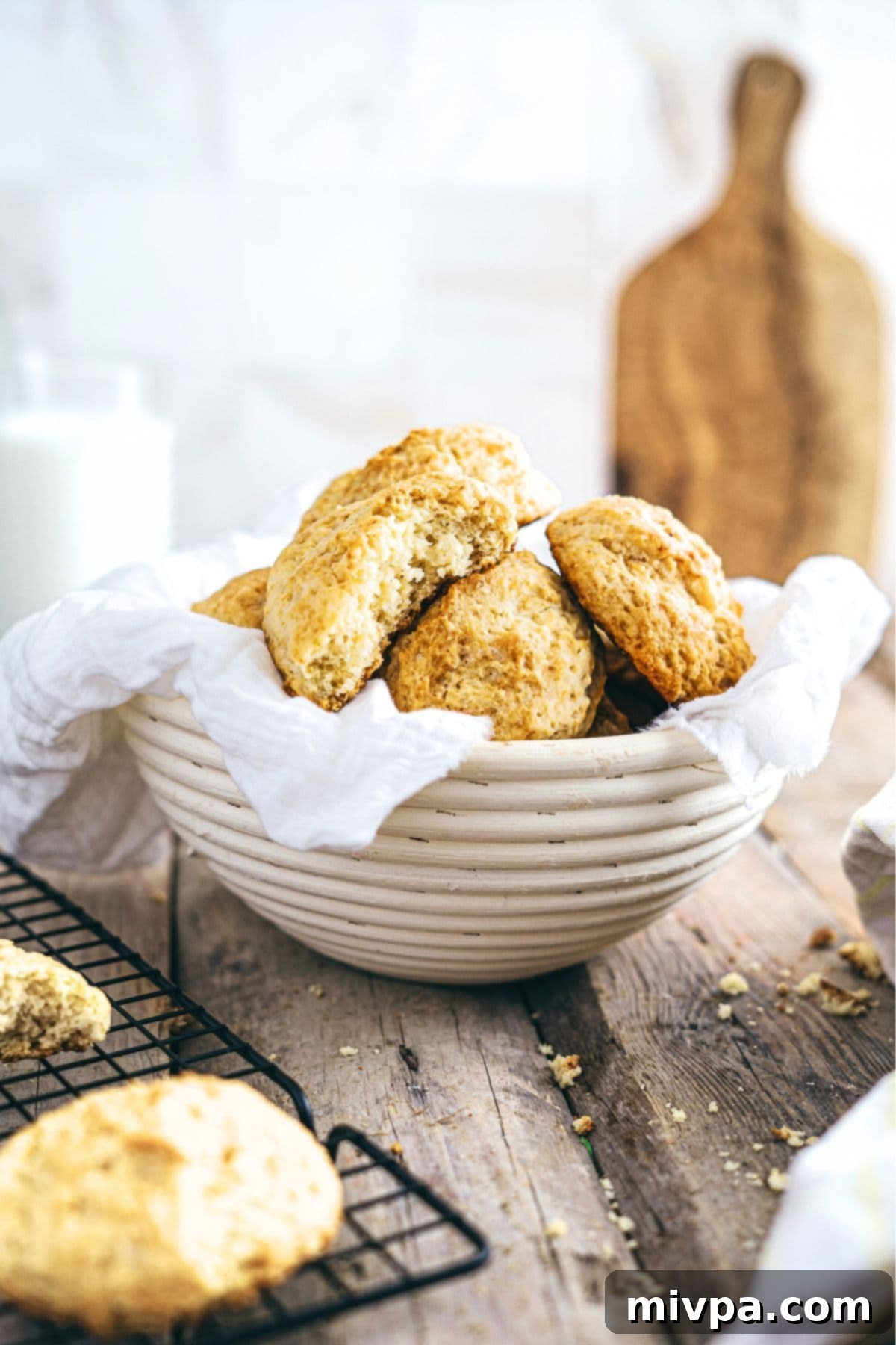 A charming basket overflowing with freshly baked gluten-free drop biscuits on a rustic wooden board.