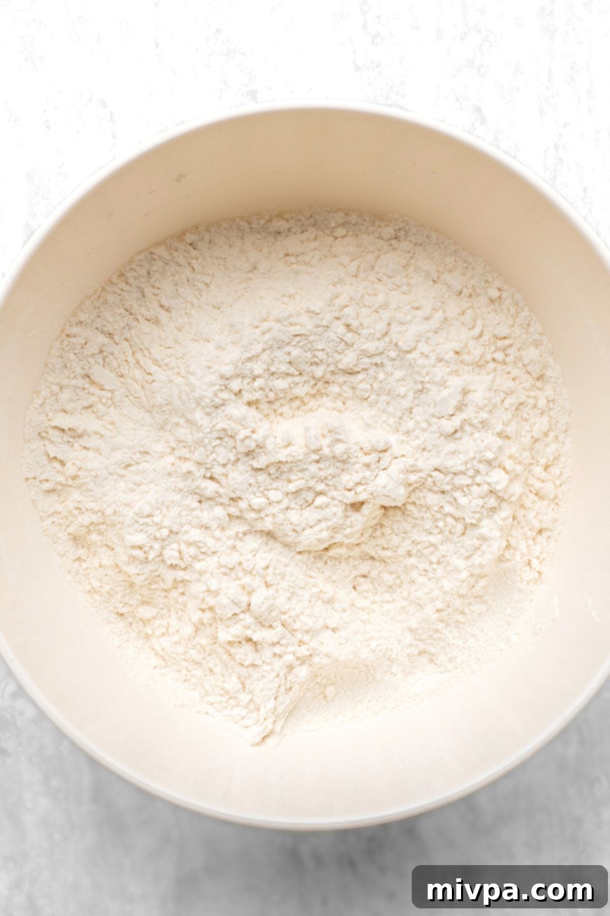 A large bowl containing a well-mixed blend of dry gluten-free flour, leavening agents, and sugar.