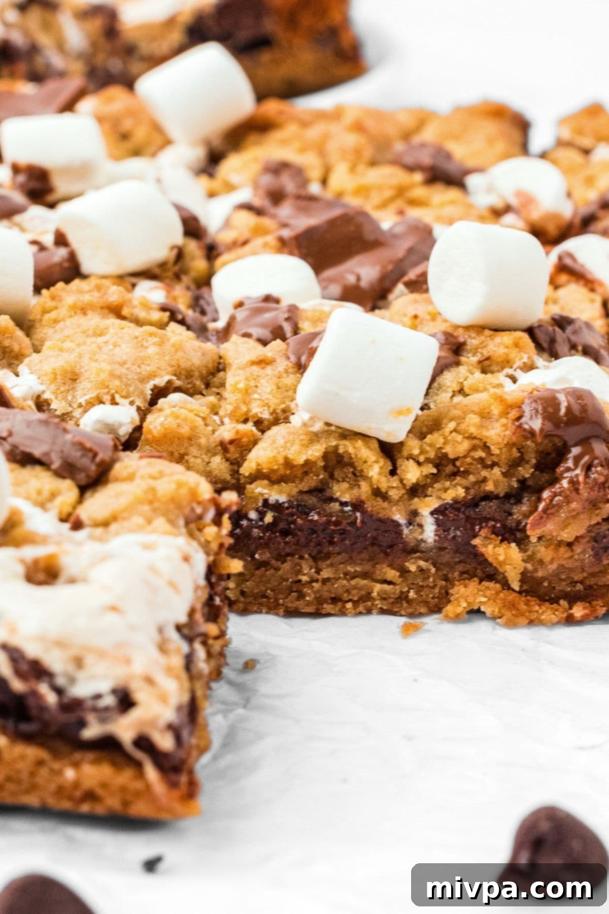 A close-up of half-eaten gluten-free s'mores cookie bars, showing their rich, layered texture and inviting gooeyness.