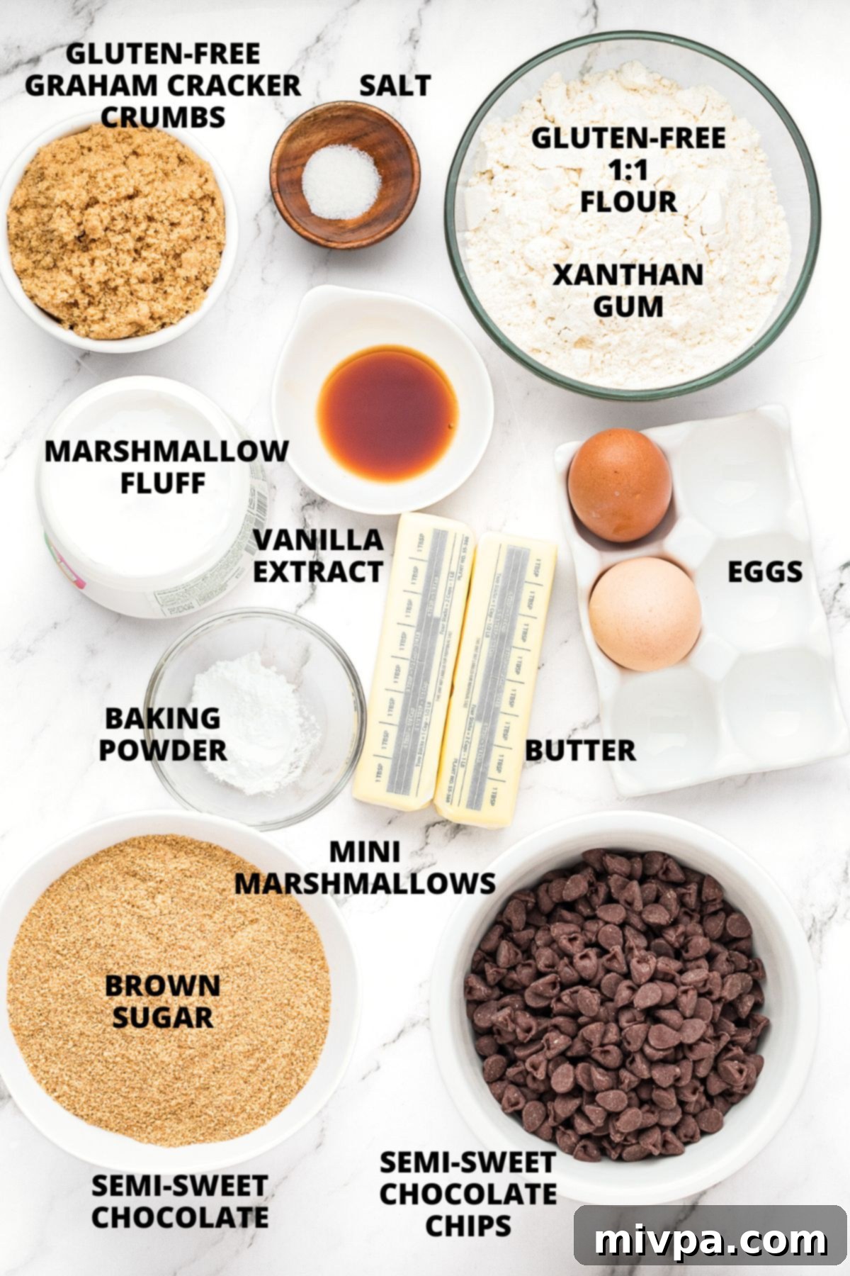 A curated spread of all ingredients necessary for making gluten-free s'mores bars, neatly arranged on a stylish marble board, ready for preparation.