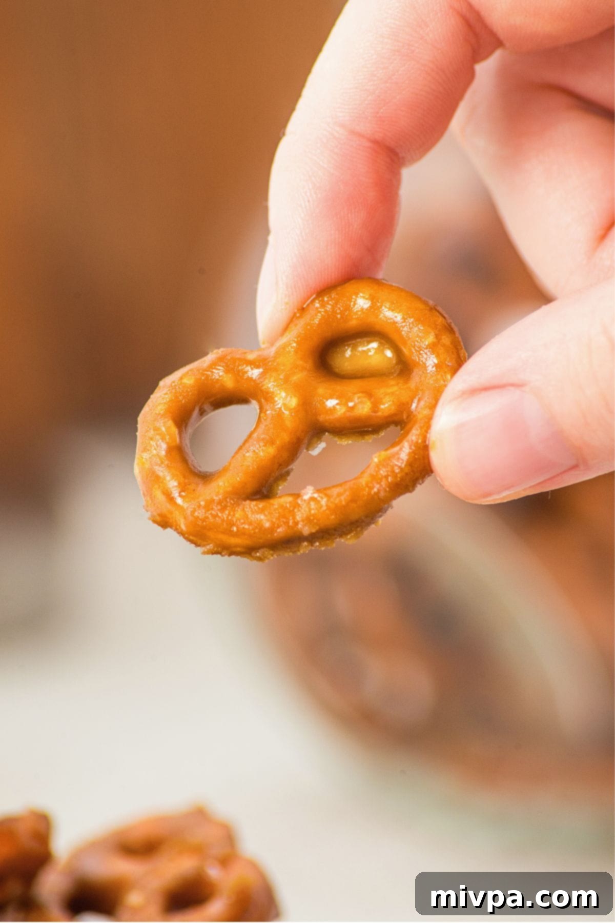 Gluten & Dairy-Free Toffee Pretzels Ready to Eat A hand holding up a perfectly set, crunchy butter toffee pretzel, ready to be enjoyed.