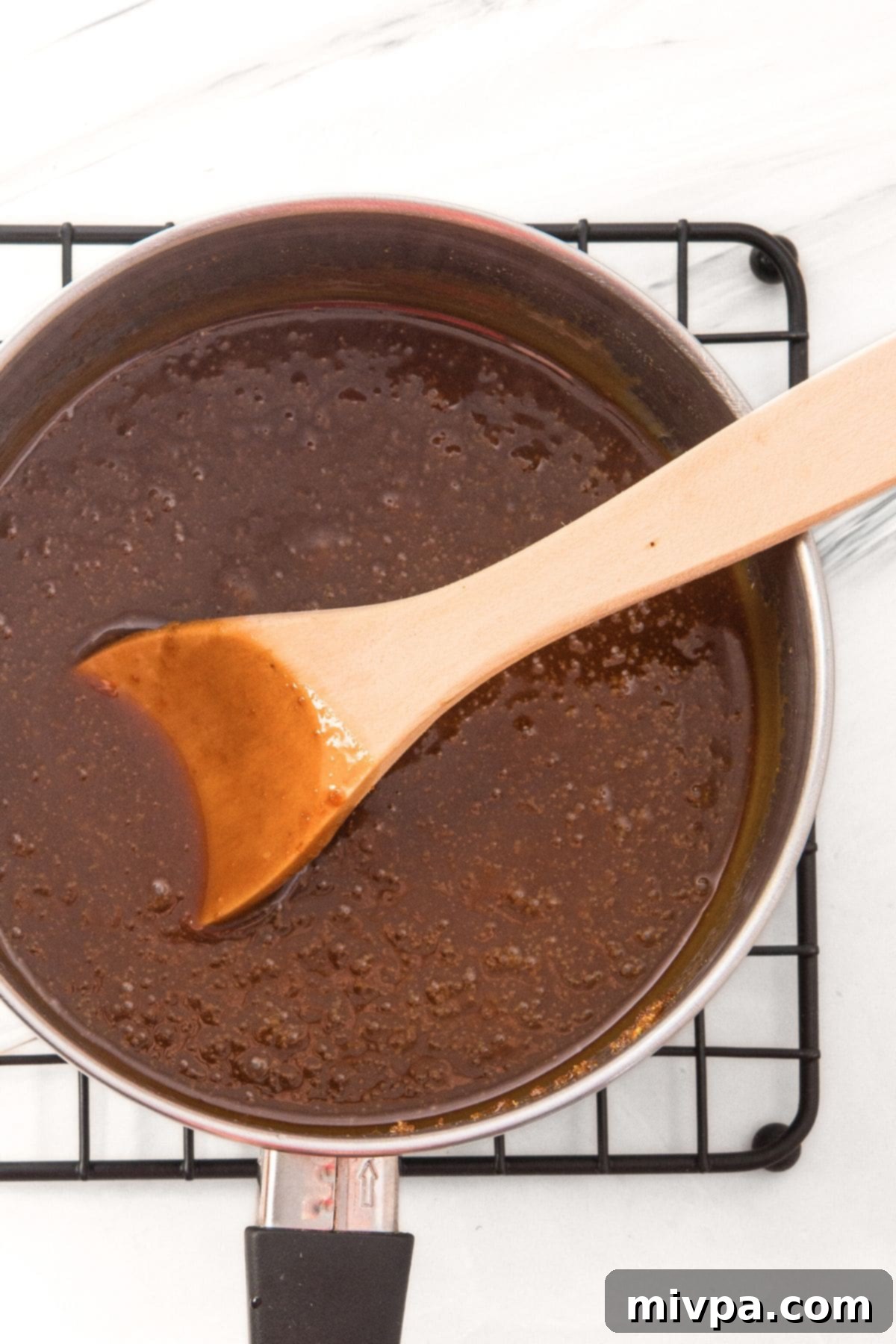 Cooking the Toffee Mixture for Toffee Butter Mini Pretzels A rich, golden brown toffee mixture bubbling gently in a saucepan on the stovetop.