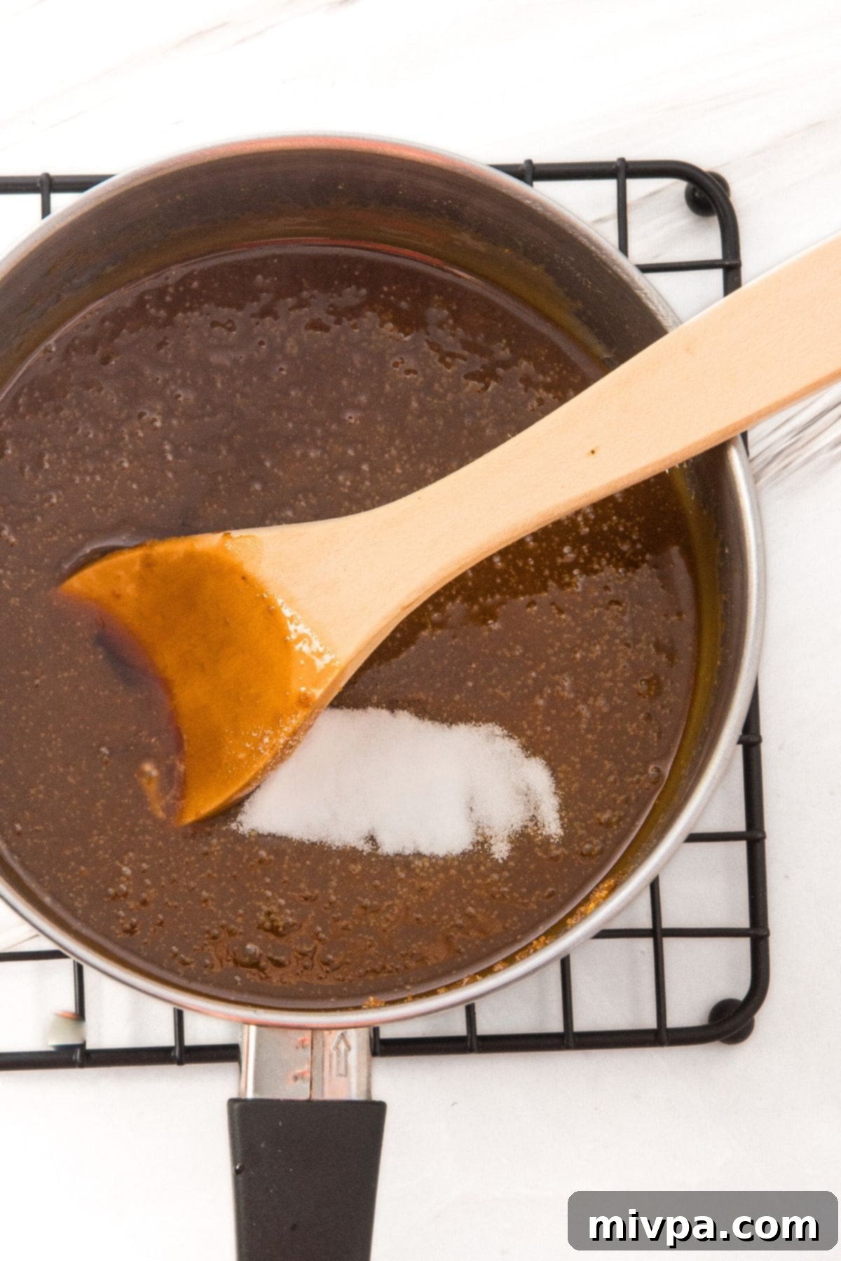 Adding Baking Soda to Toffee for Homemade Mini Pretzels Baking soda being added to the hot, foaming toffee mixture in the saucepan.