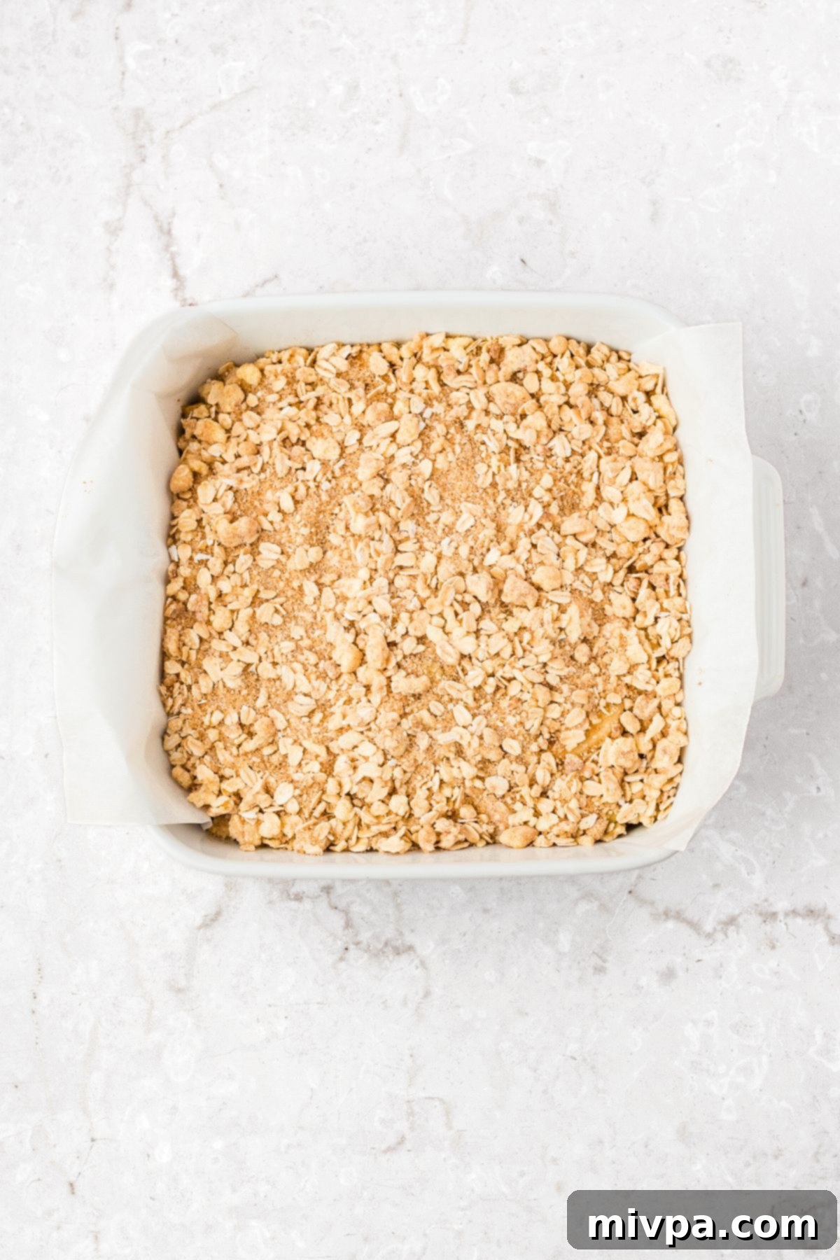 Gluten-Free Apple Pie Bar Recipe (Vegan) Crumble mixture sprinkled over the apple layer in a baking dish.