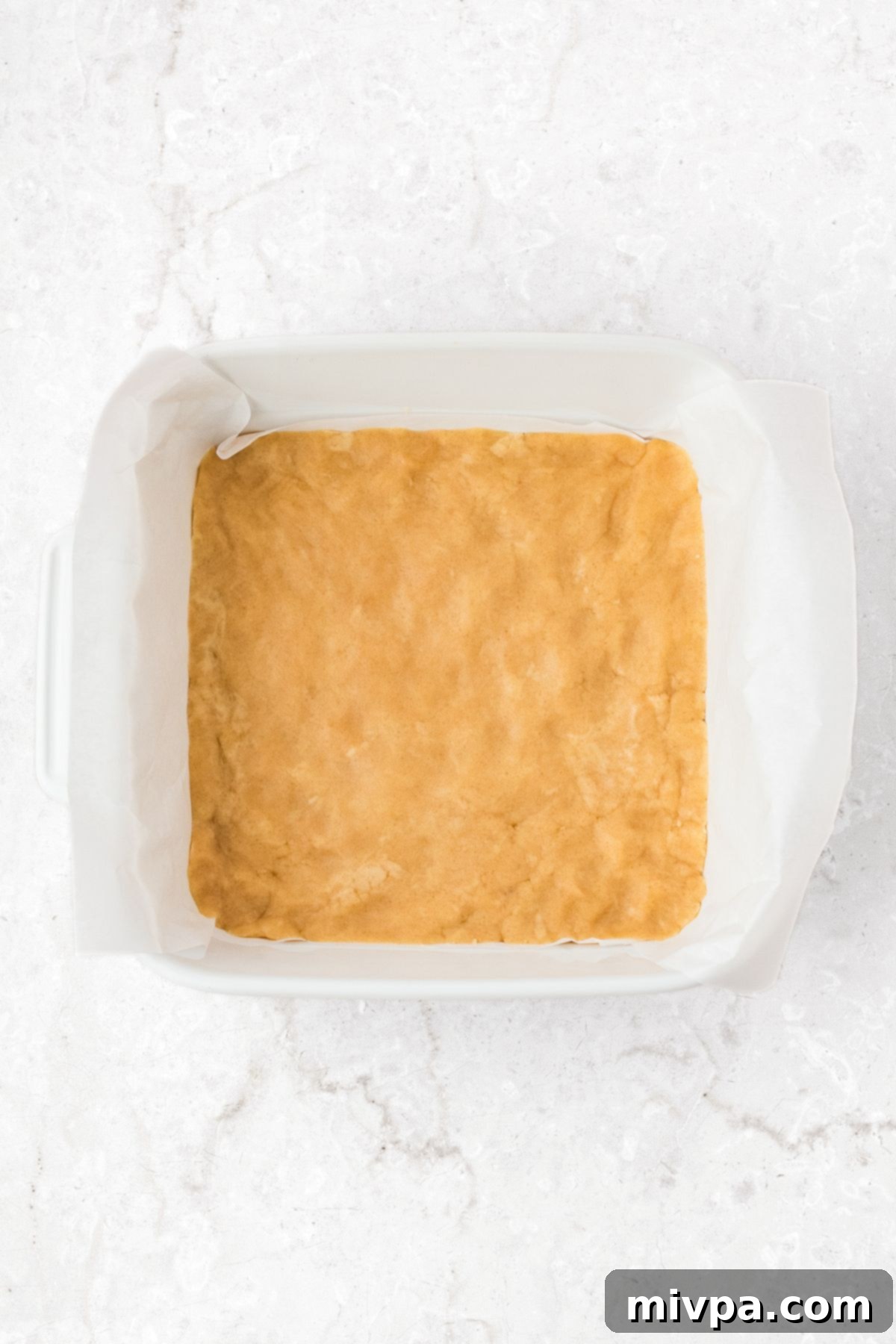 Easy Apple Pie Squares Pressing the crust dough into a parchment-lined baking dish.