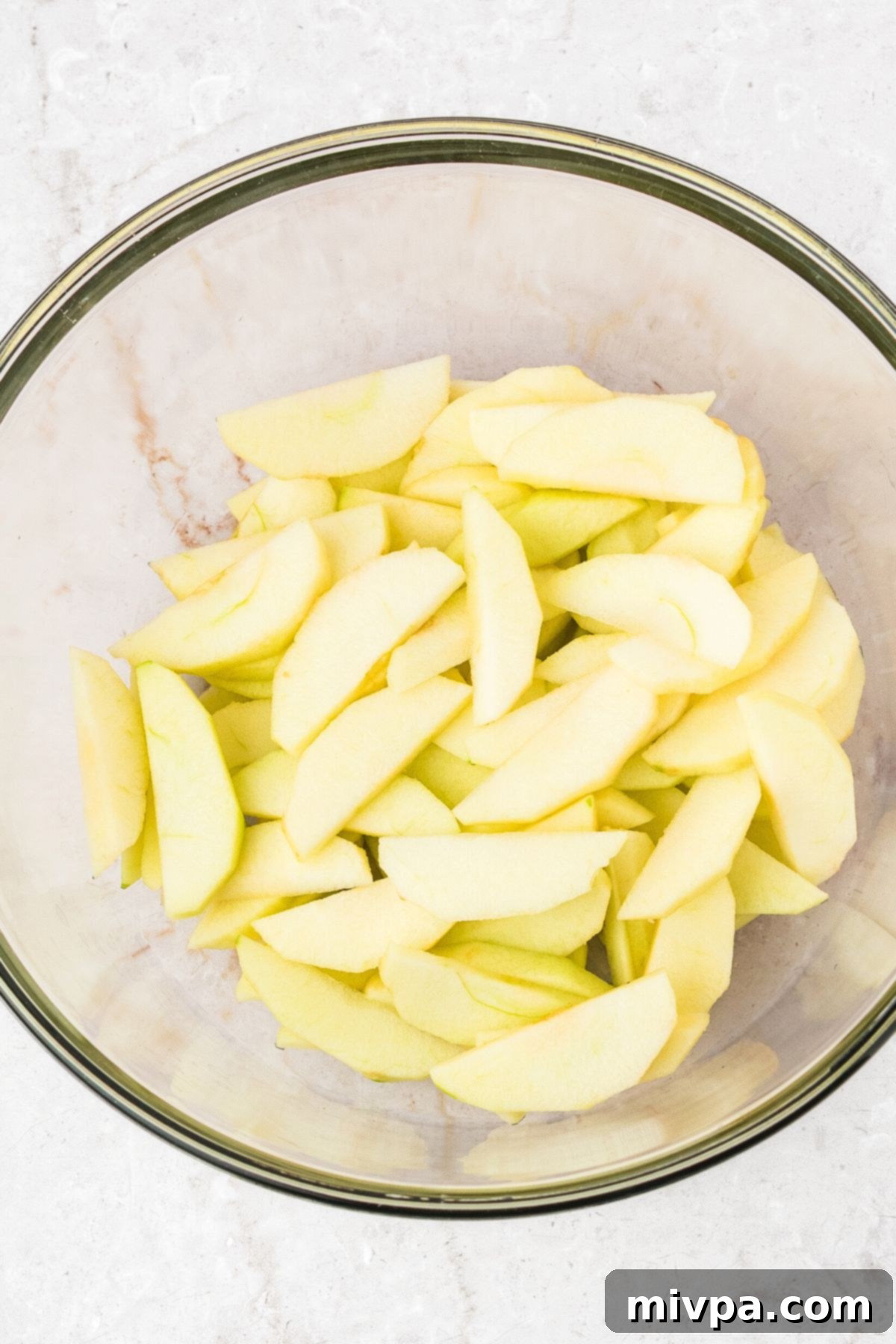 Apple Pie Bar Recipe Sliced apples in a glass bowl, ready for seasoning.