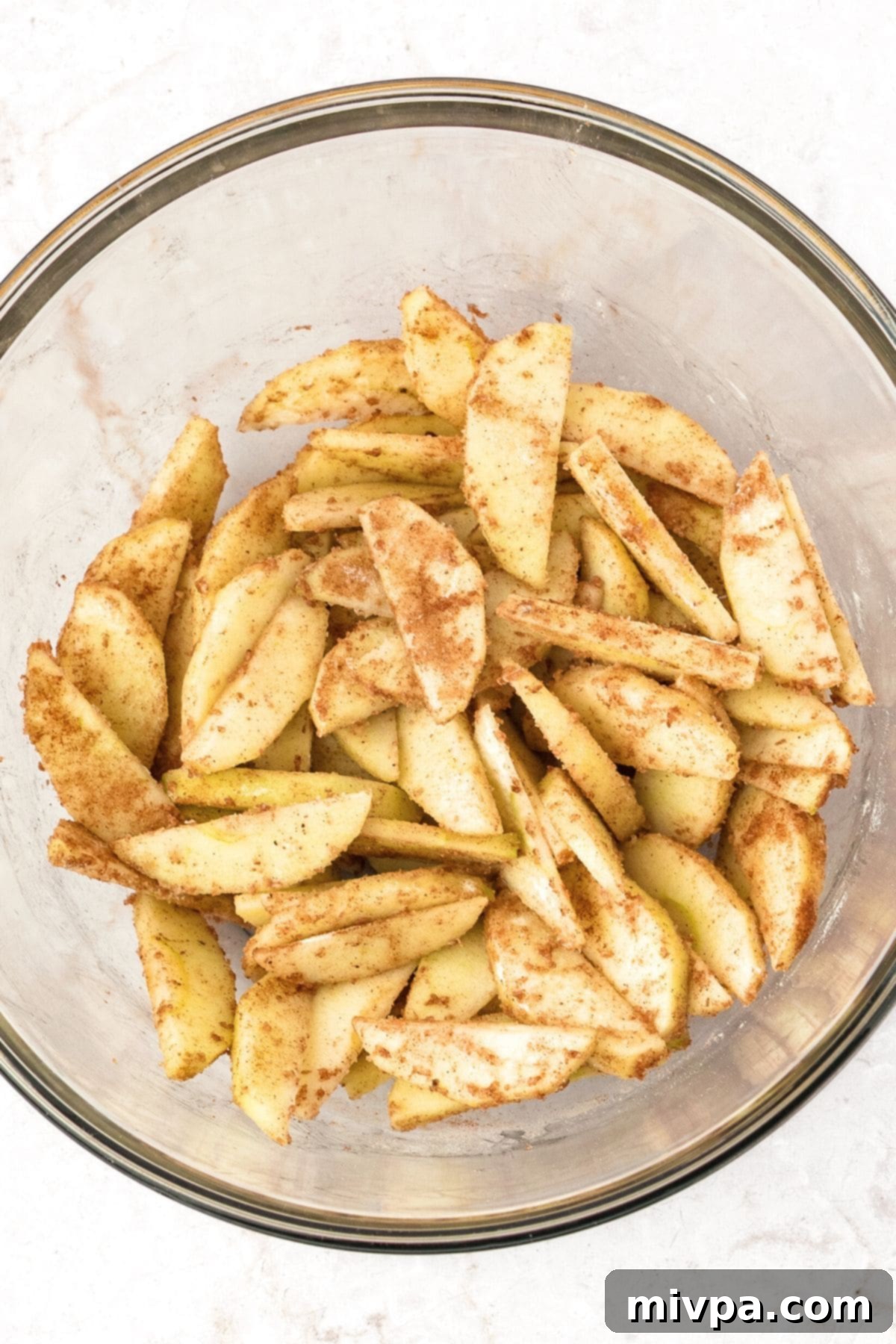 Gluten Dairy-Free Apple Pie Bars Sliced apples tossed in warming spices in a large bowl.