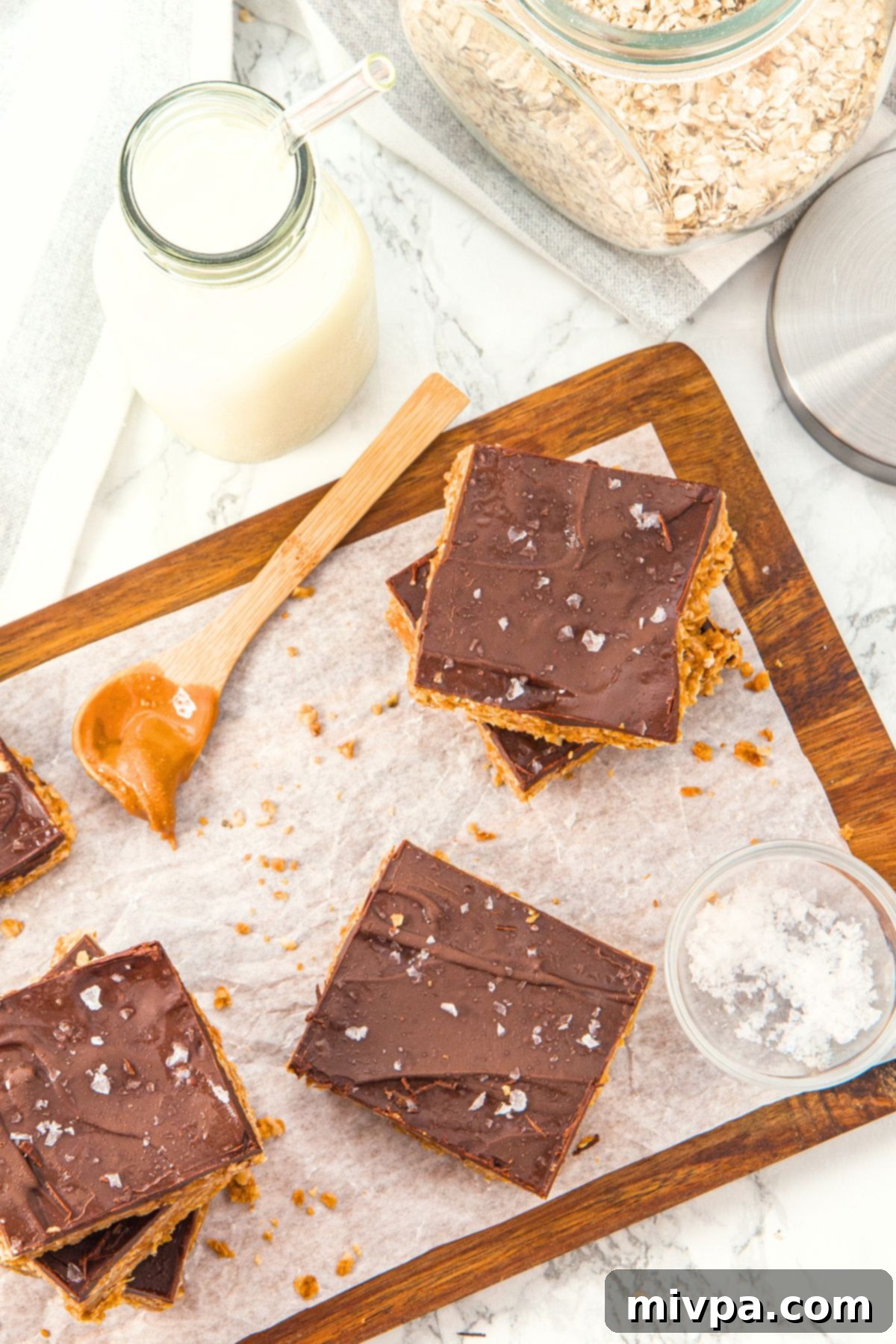Peanut Butter Chocolate Oat Bars (Gluten-Free, Vegan) Top-down view of freshly prepared chocolate peanut butter oat bars on a parchment-lined cutting board.
