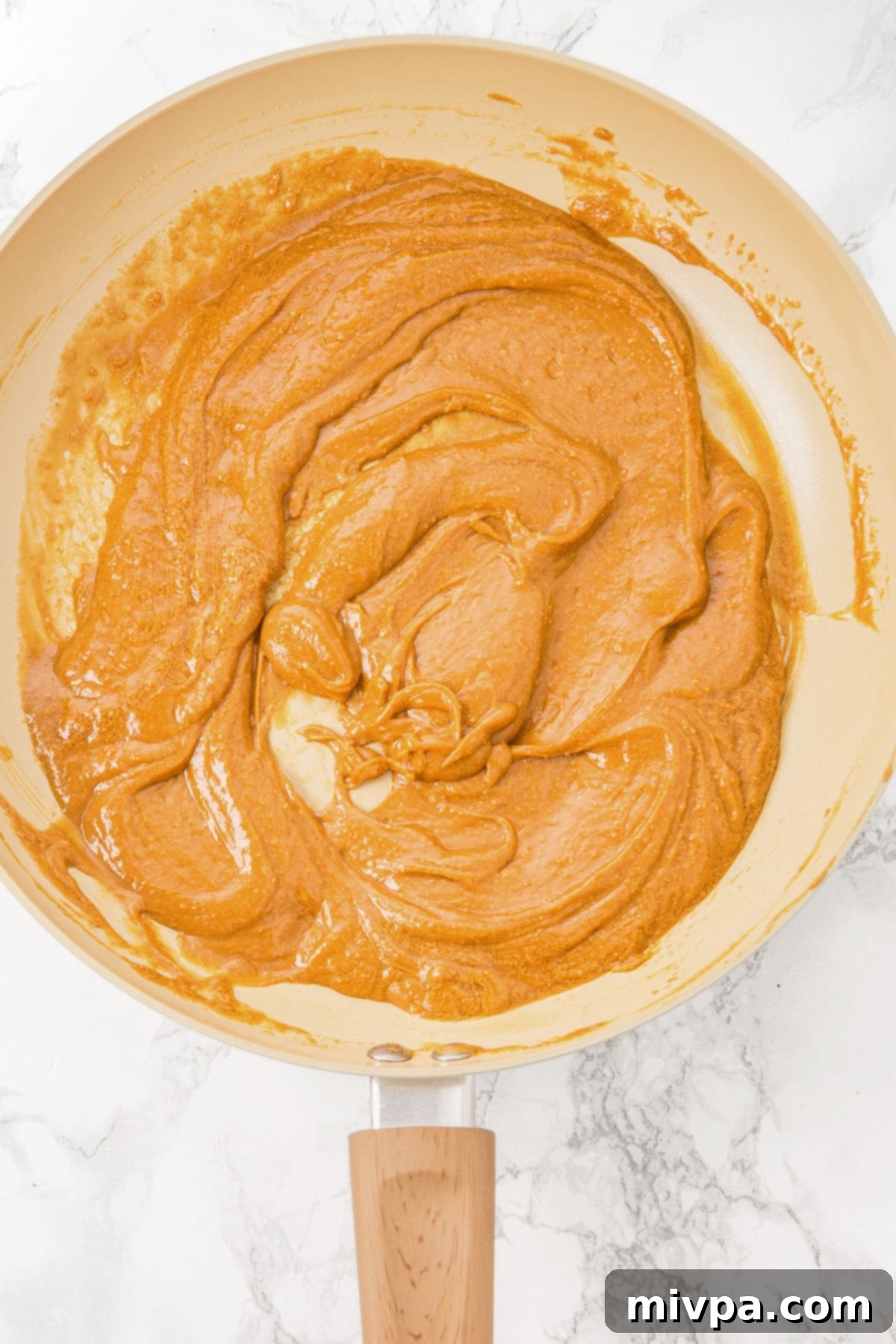 Gluten-Free Peanut Butter Oat Bars Peanut butter and maple syrup mixture in a skillet, gently heating.