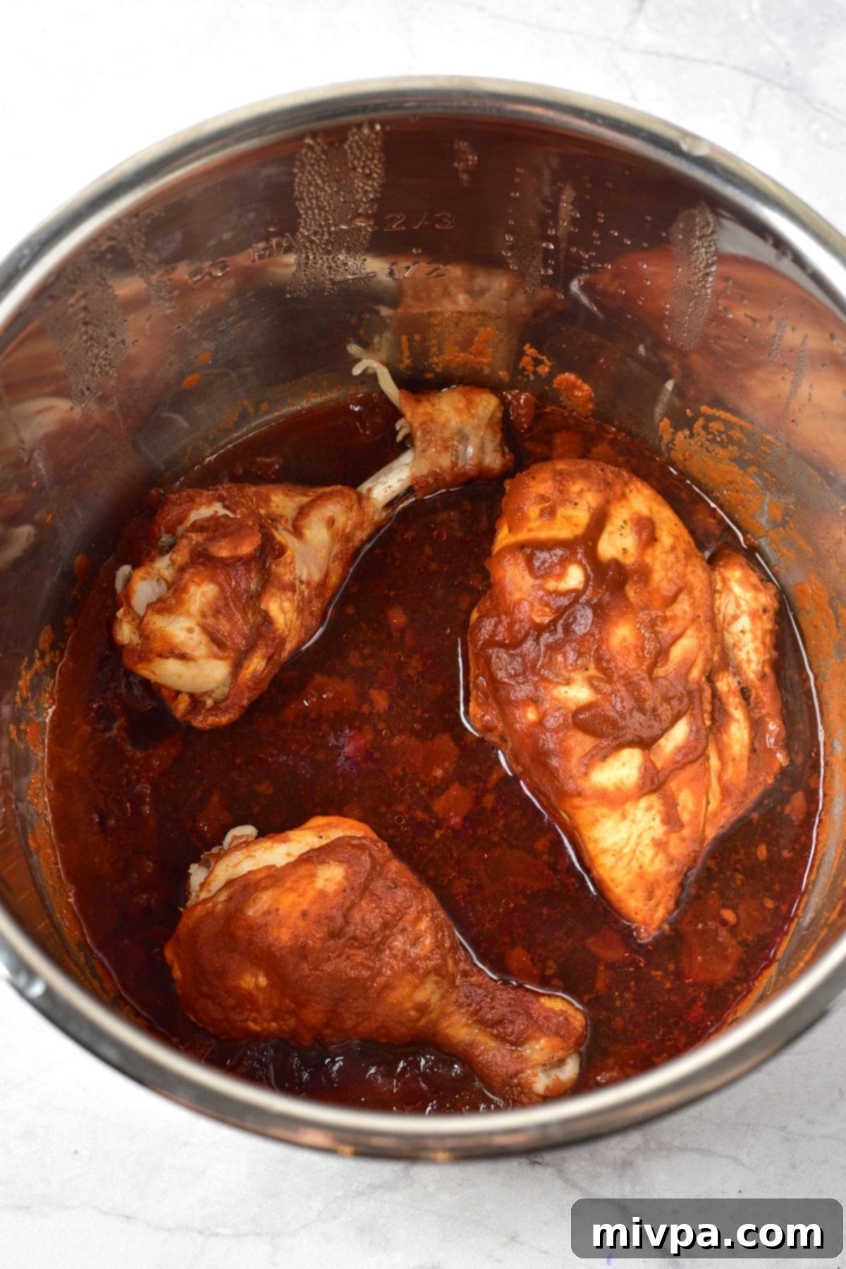 How to Make Chicken Birria (Gluten-Free, Dairy-Free) Chicken and birria sauce in a pot, simmering gently.