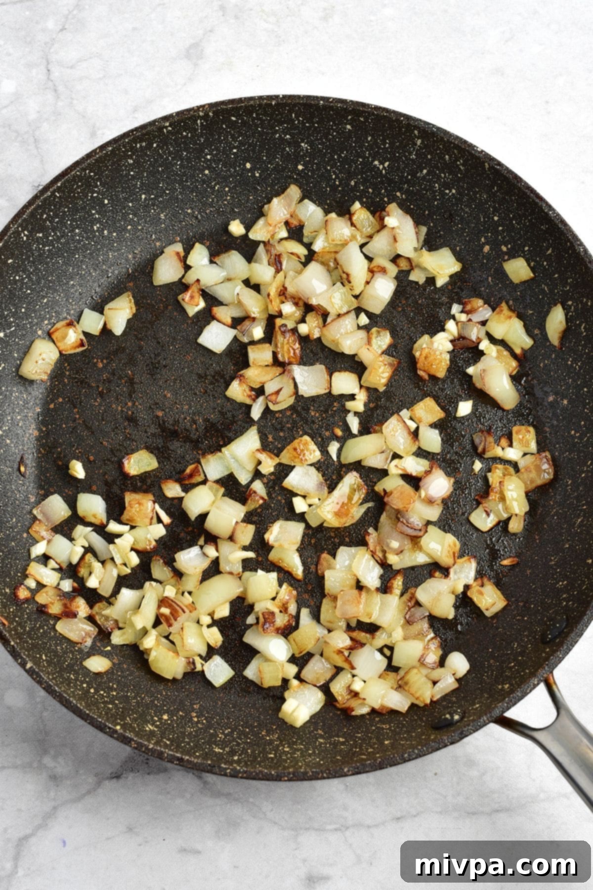 Chicken Birria Recipe (Gluten-Free, Dairy-Free) Sautéed diced onions in skillet, turning golden brown.