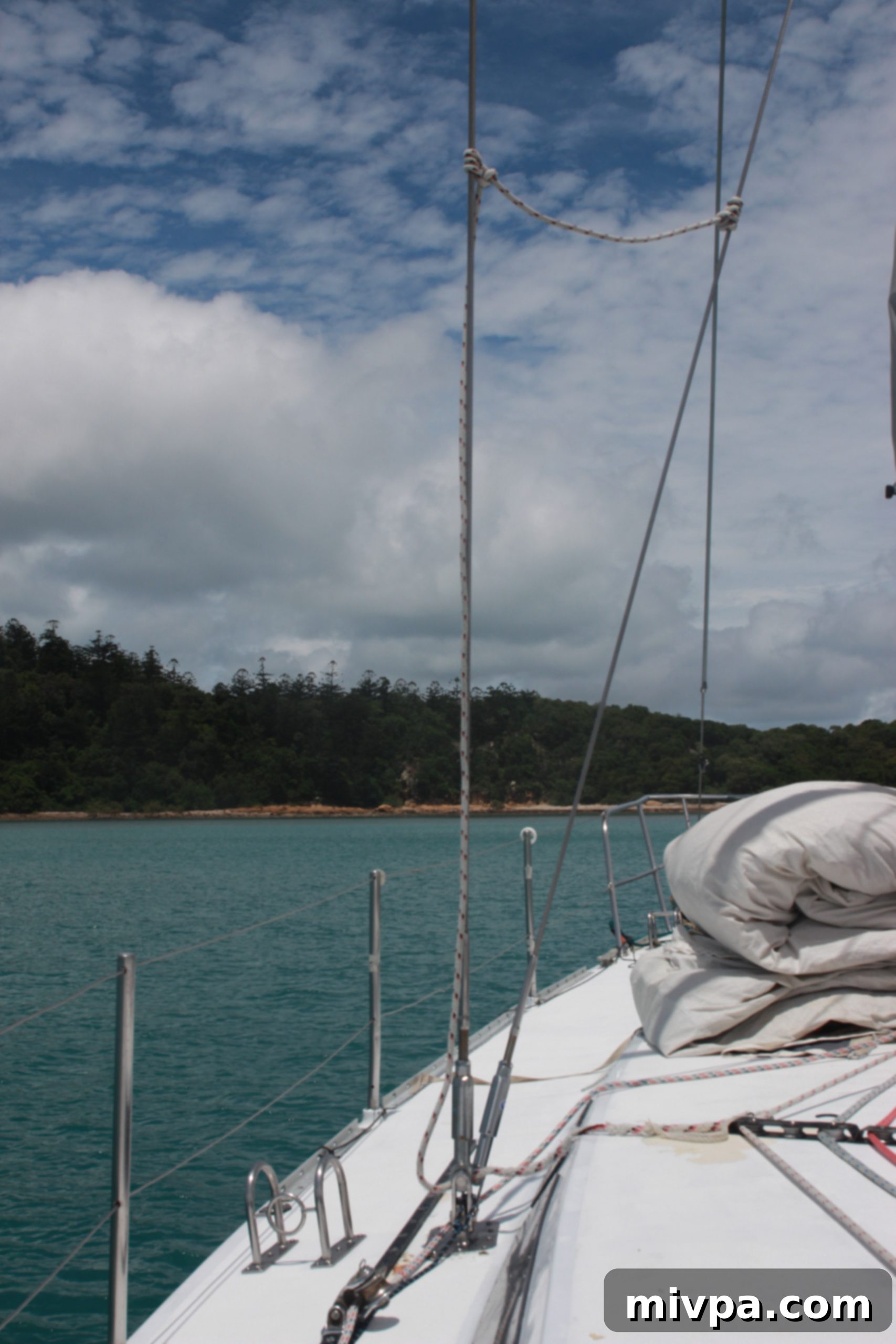 Smiling woman standing confidently at the stern of a sailboat with ocean views
