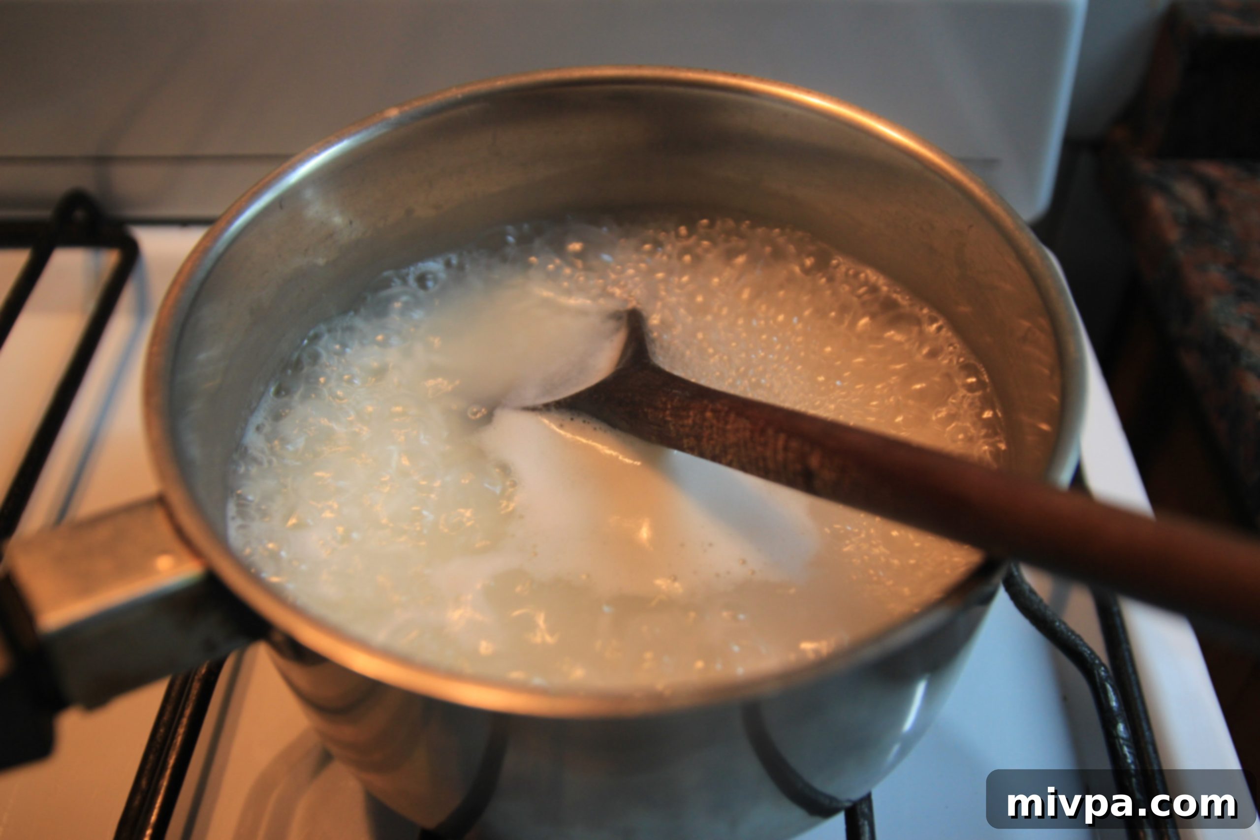 Rice and water boiling in a small pot before reducing heat to simmer.