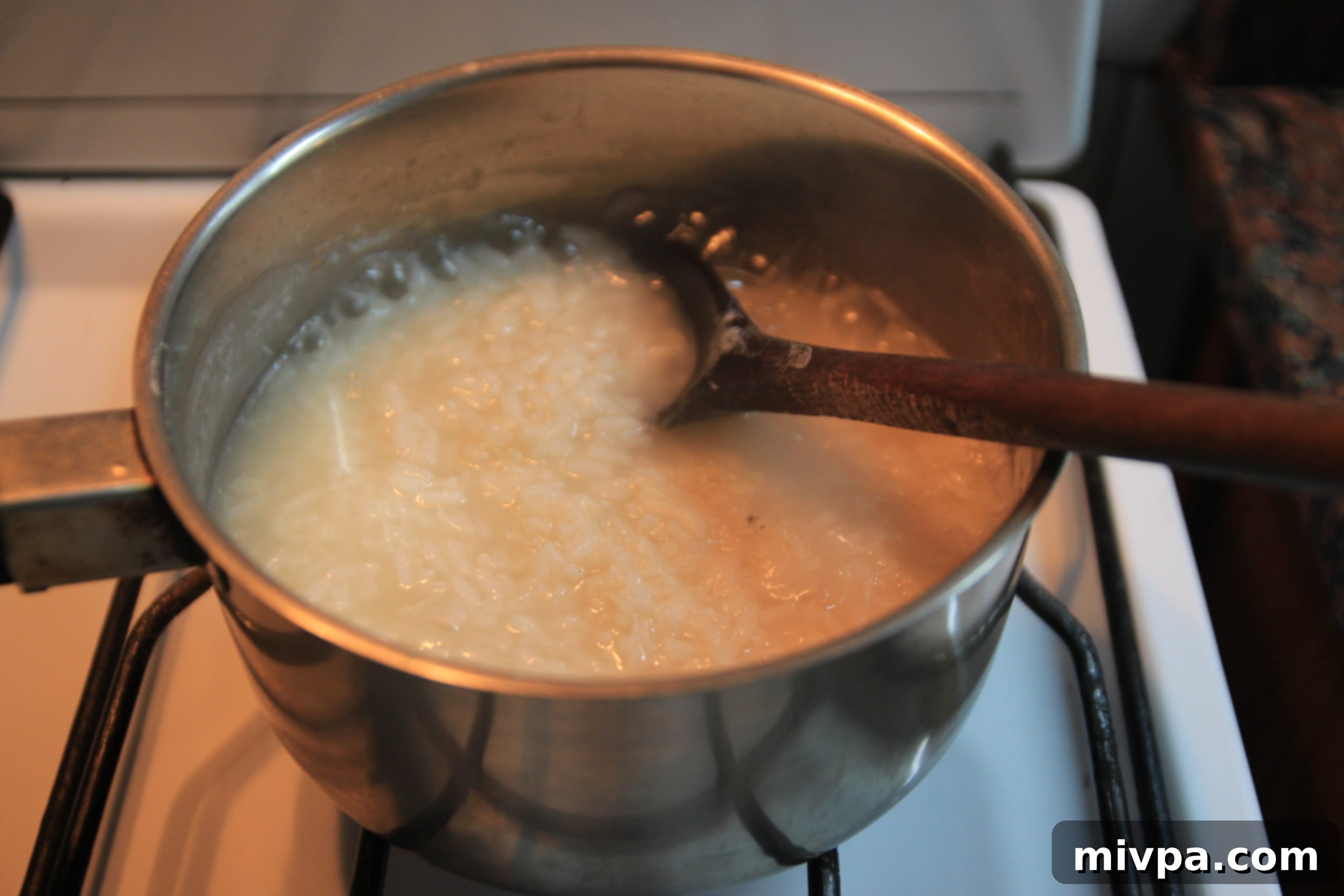 More water being added to partially cooked rice in a pot.