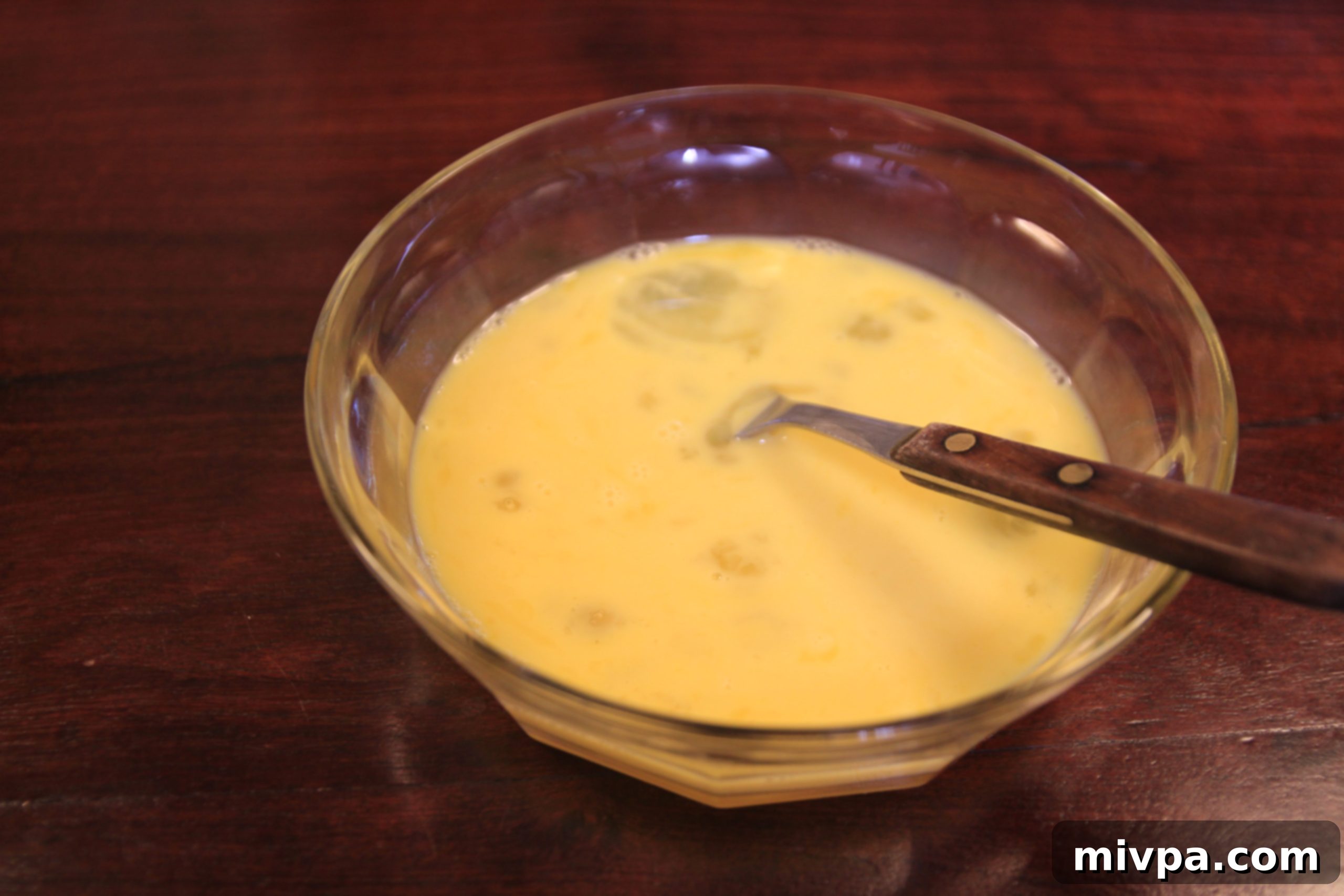 Beaten eggs in a bowl, forming a smooth yellow mixture.