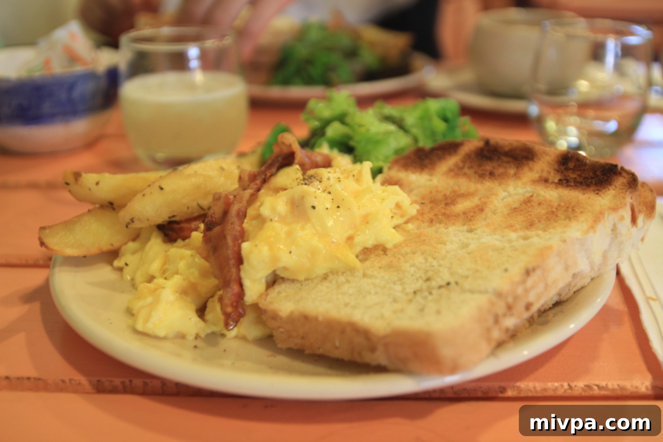 Delicious Huevos Completos brunch with scrambled eggs, bacon, potatoes, and salad at Oui Oui Cafe