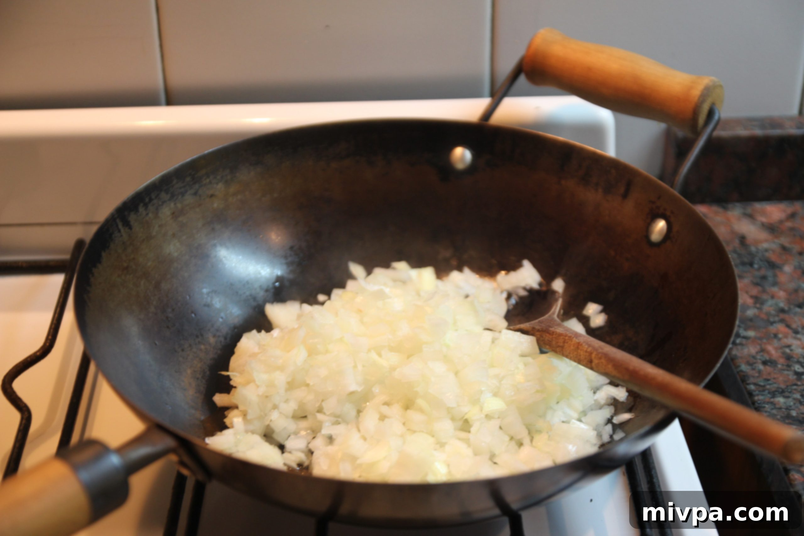 Diced onions sizzling in a wok, beginning to soften