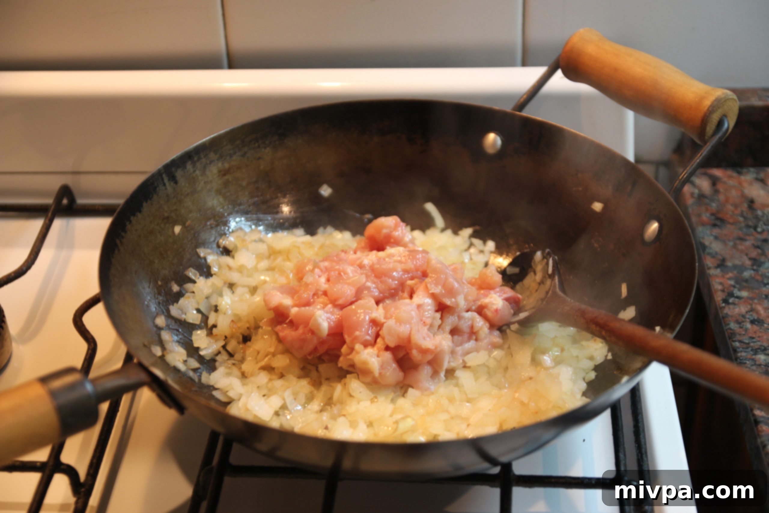 Chicken strips added to the caramelized onions in the wok