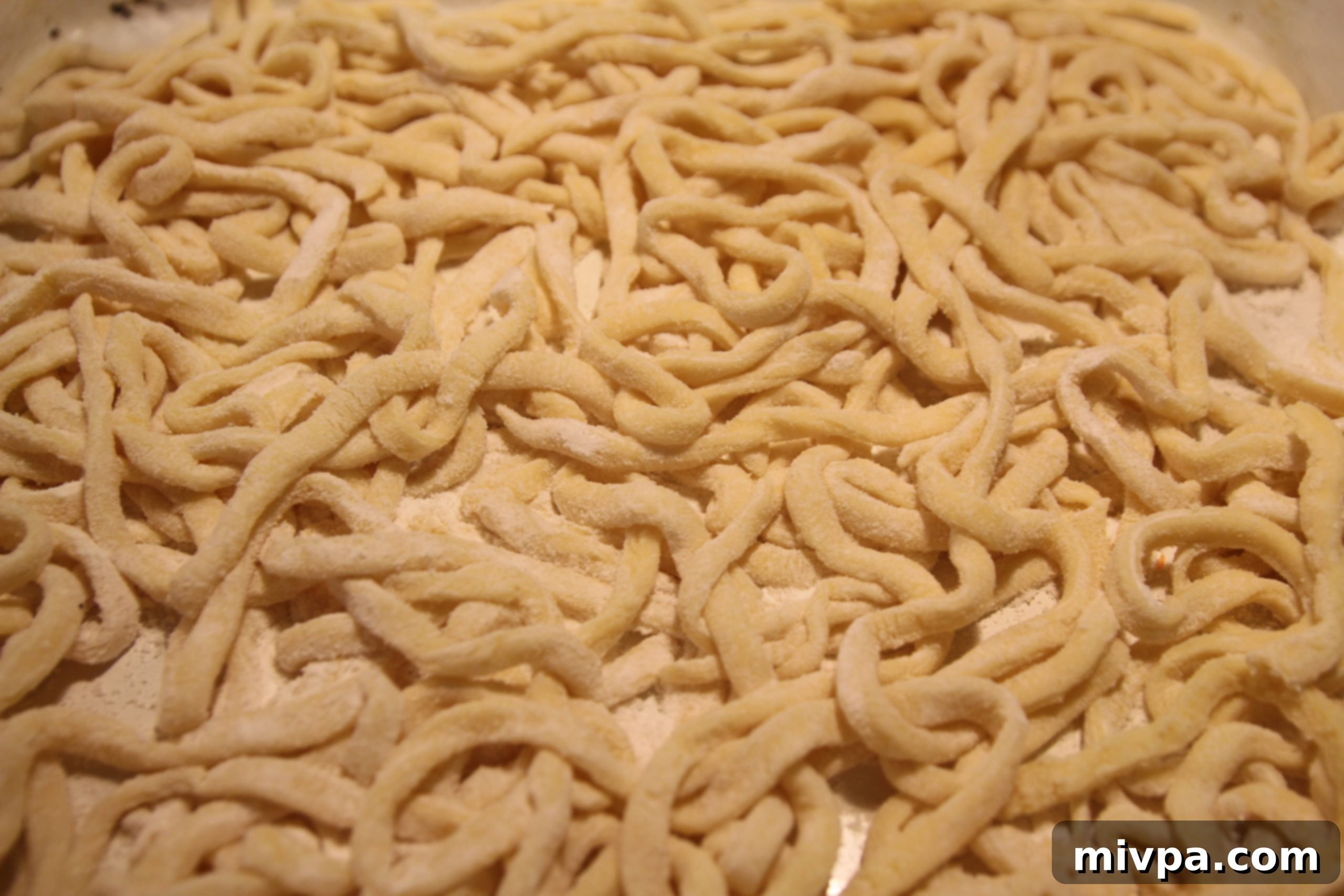 A generous pile of freshly made tagliatelle pasta on a wooden board.