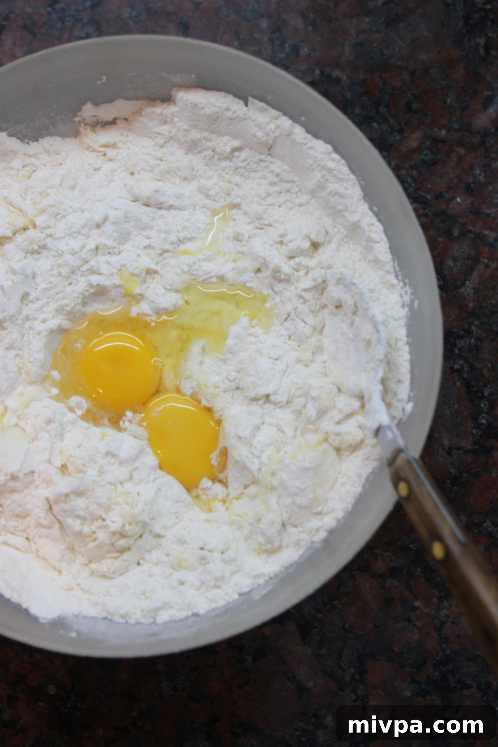 Mixing flour and eggs on a clean surface to form dough.