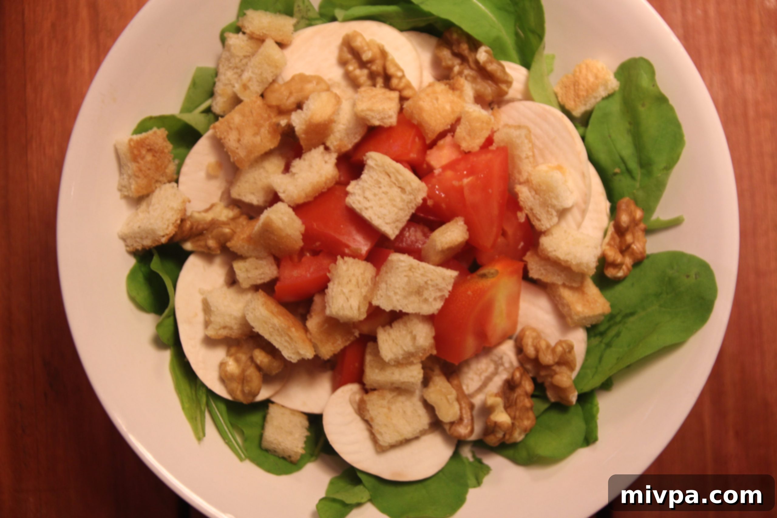Close-up of Arugula, Mushroom, Tomato & Walnut Salad being tossed with dressing