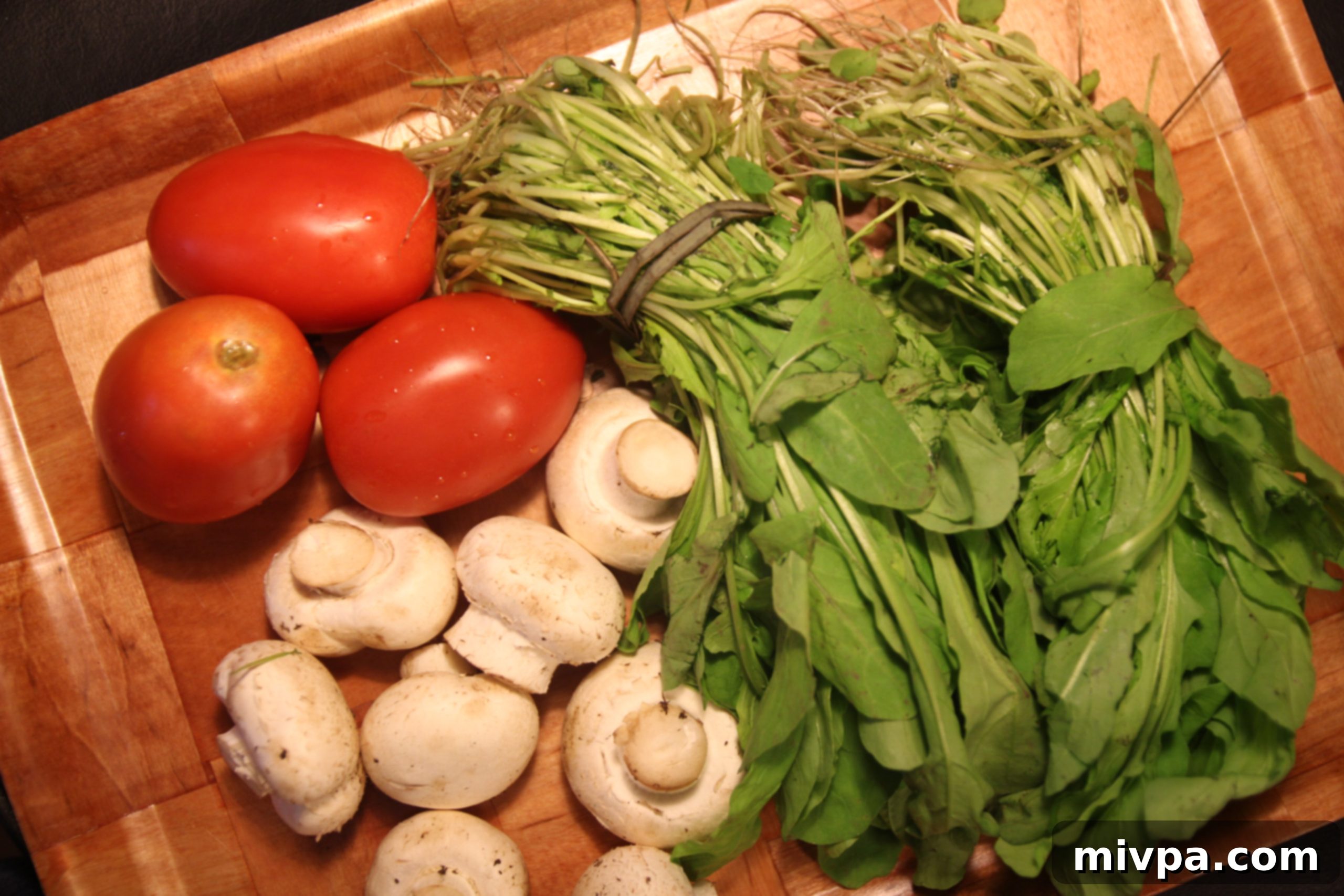 Assortment of fresh vegetables, including arugula, mushrooms, and tomatoes, neatly arranged