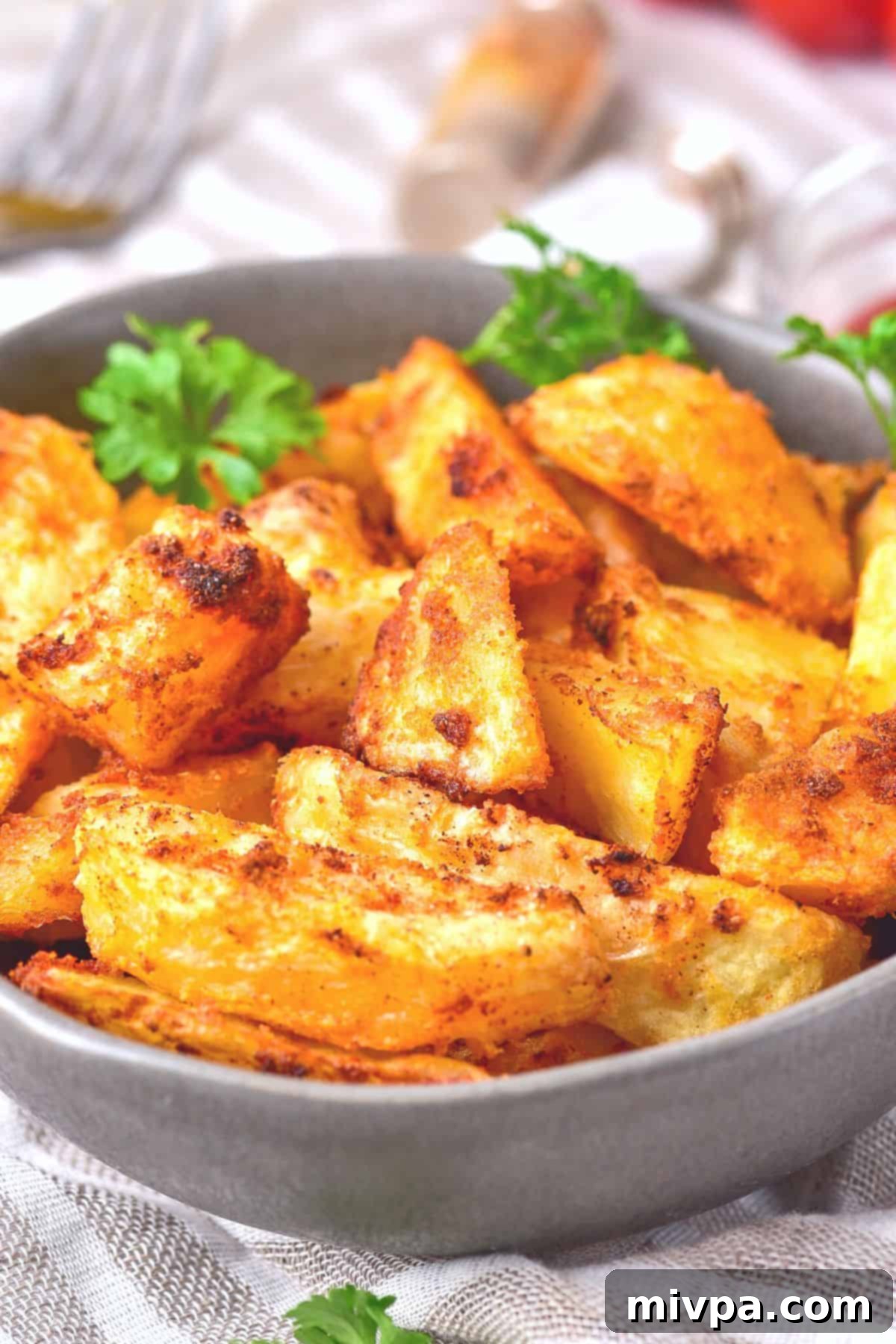 A bowl of crispy air fried potato wedges garnished with parsley, ready to be served.