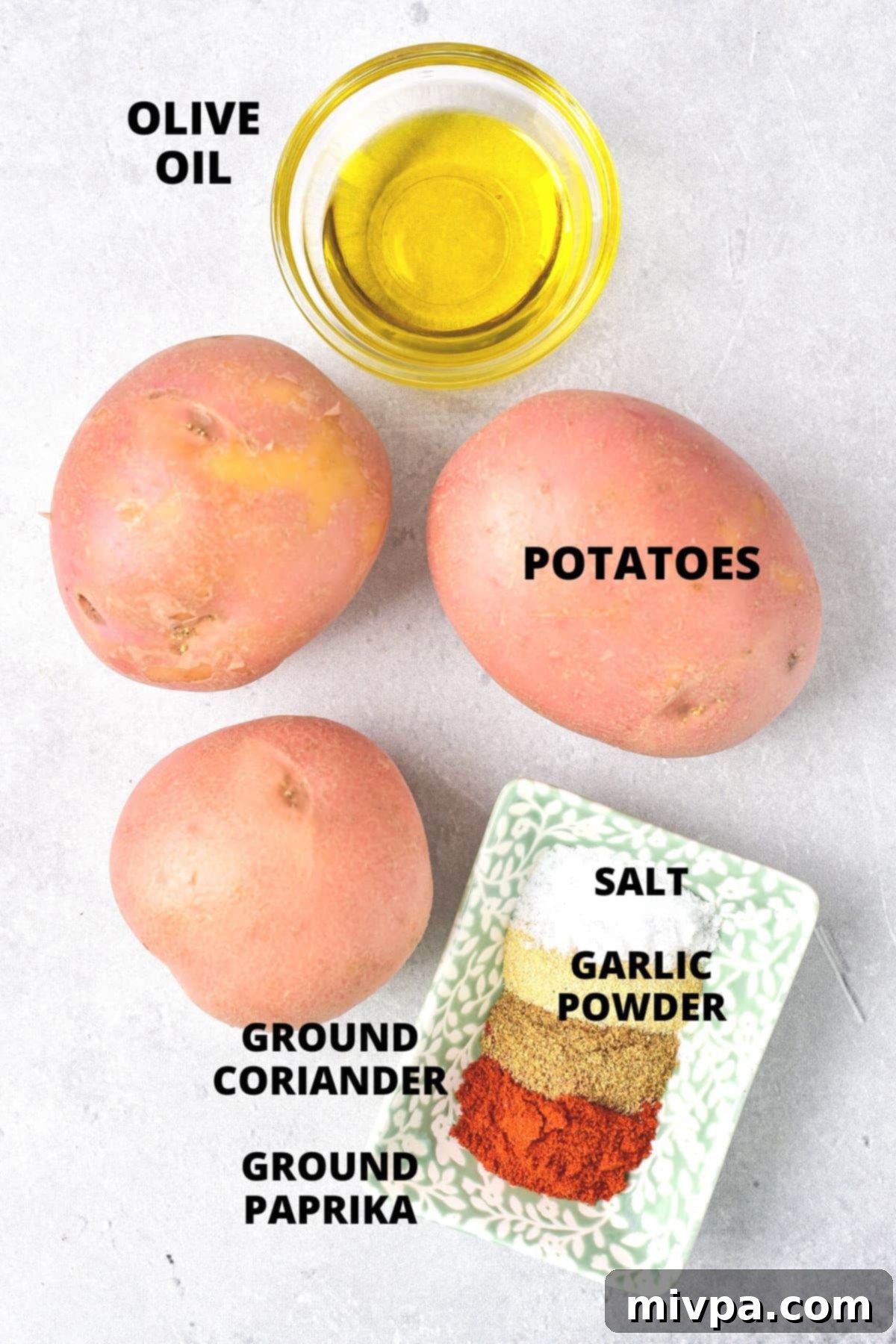 A selection of ingredients laid out for air fried potato wedges recipe, including potatoes, spices, and olive oil.