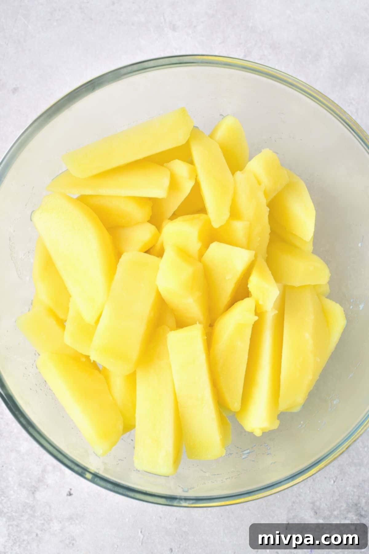 Boiled potato wedges, perfectly tender, resting in a glass bowl.