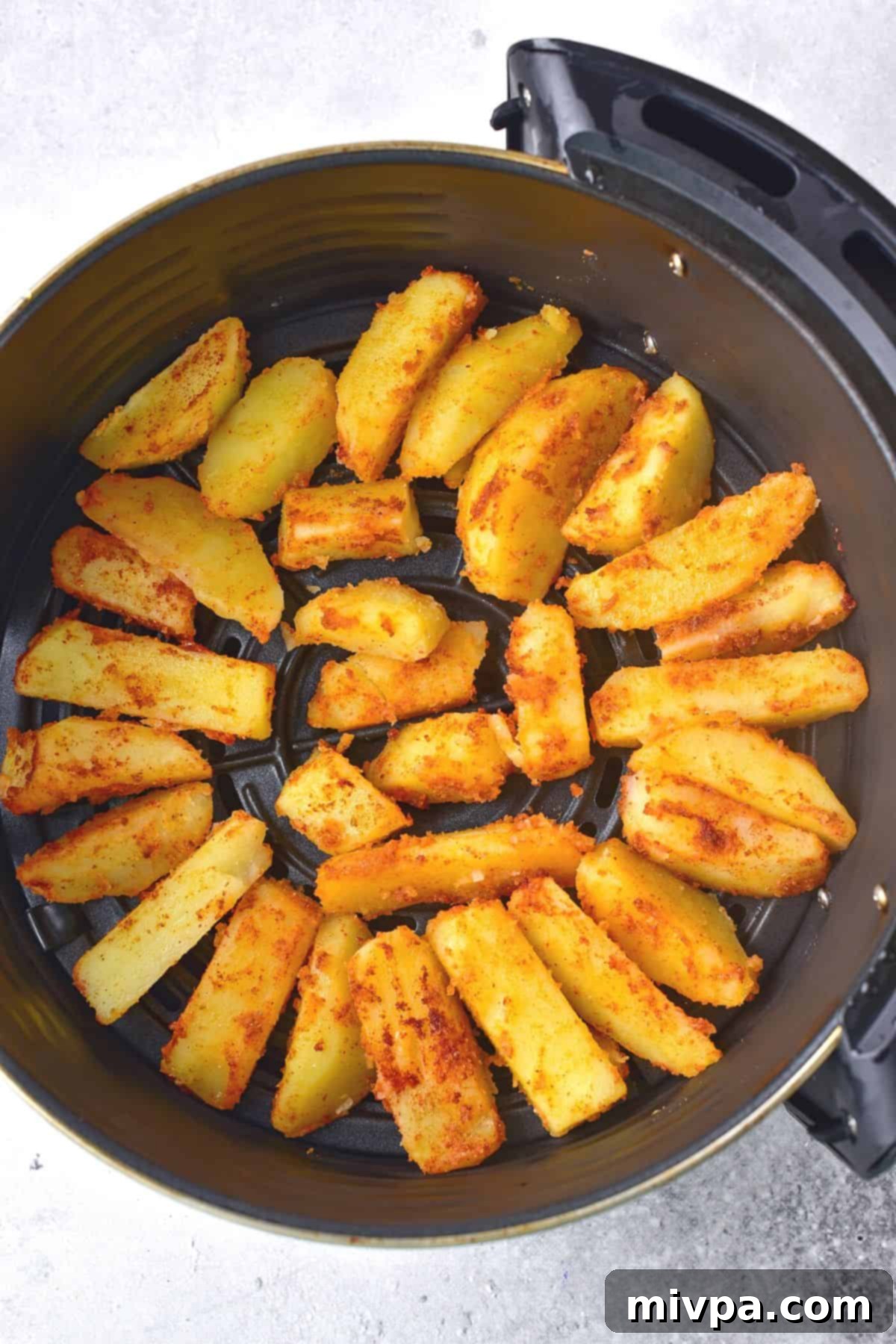 Seasoned potato wedges neatly arranged in a single layer inside an air fryer basket.