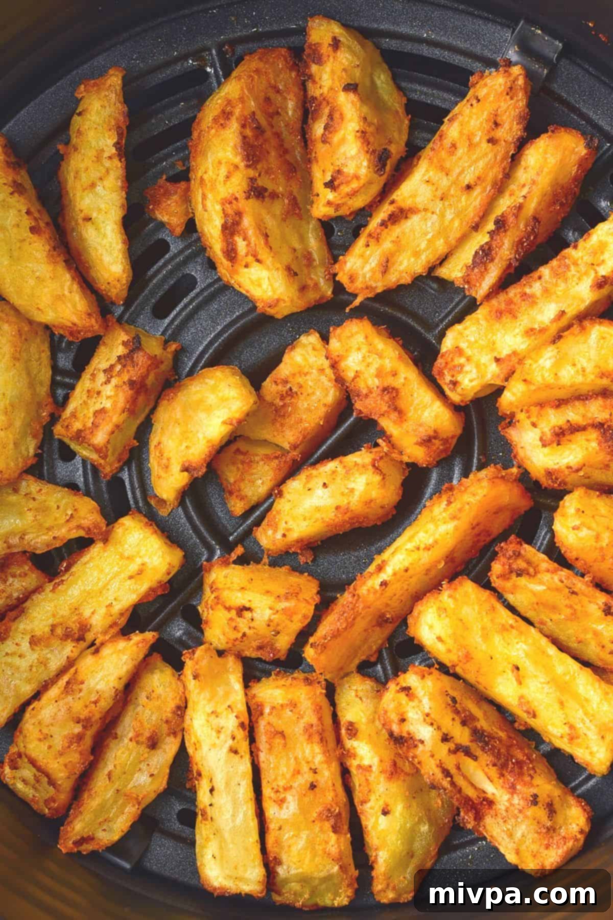 Perfectly crispy air fryer potato wedges, golden brown and ready to eat, shown in the air fryer basket.