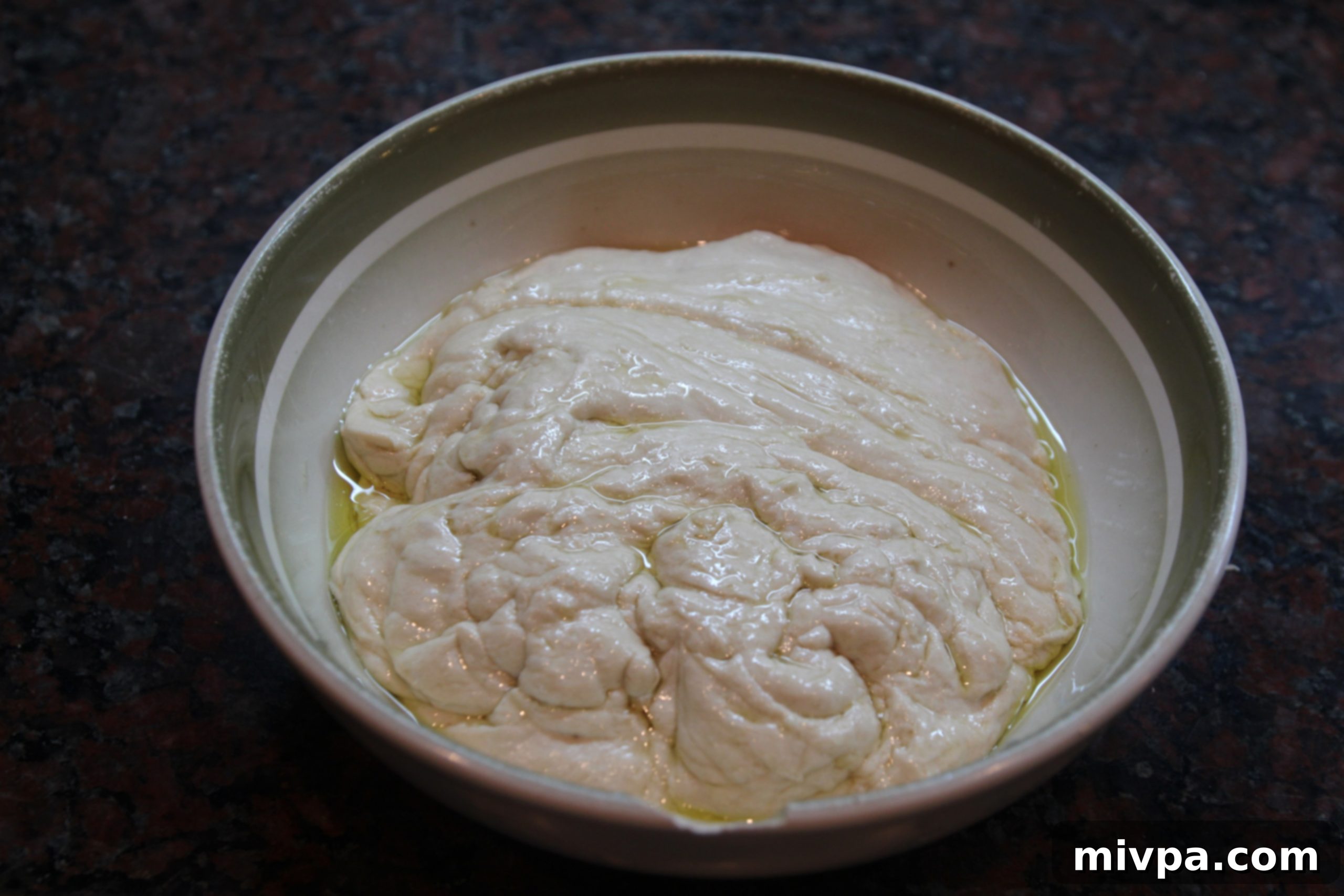 Olive oil generously coating the inside of a mixing bowl for dough rising
